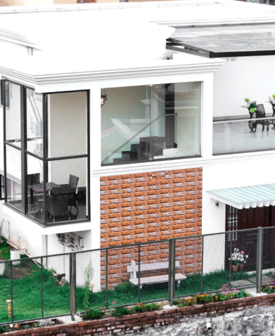 A modern white villa with glass balconies and a landscaped lawn overlooking the surrounding hills.