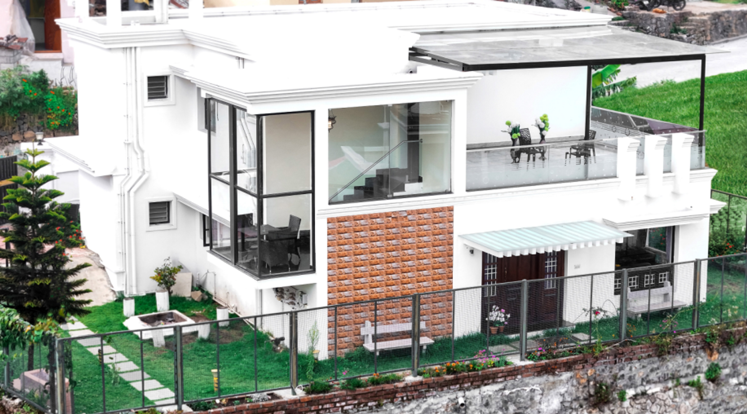 A modern white villa with glass balconies and a landscaped lawn overlooking the surrounding hills.