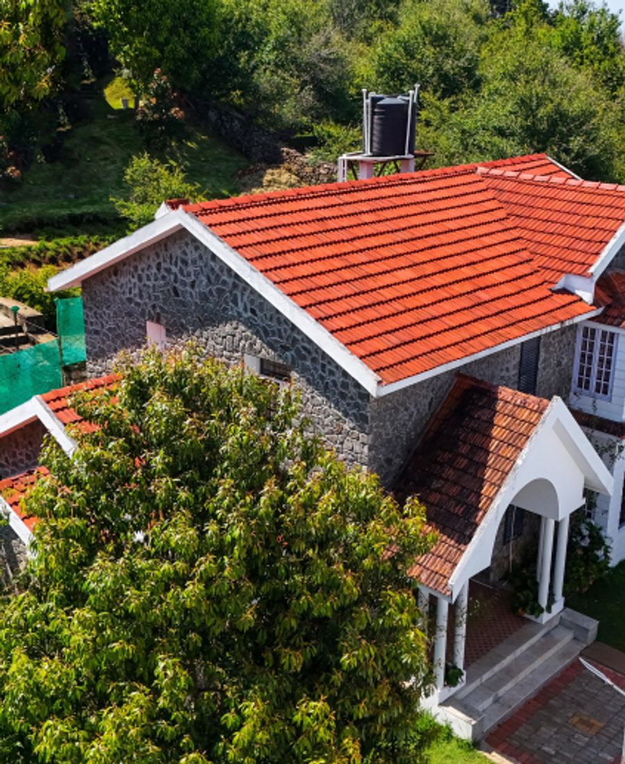 A beautifully restored red-tiled heritage home nestled amidst the lush greenery of Kodaikanal.