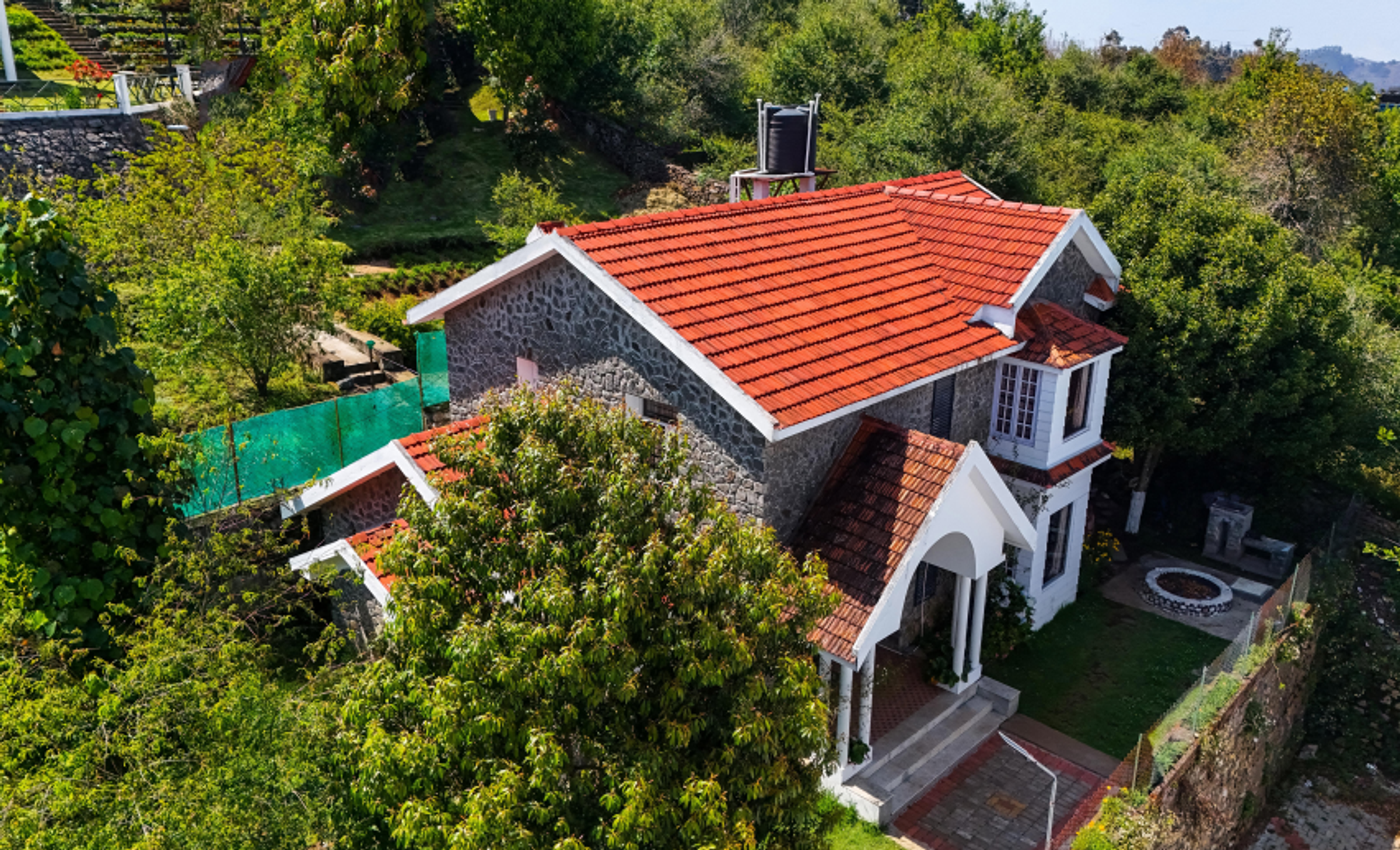 A beautifully restored red-tiled heritage home nestled amidst the lush greenery of Kodaikanal.