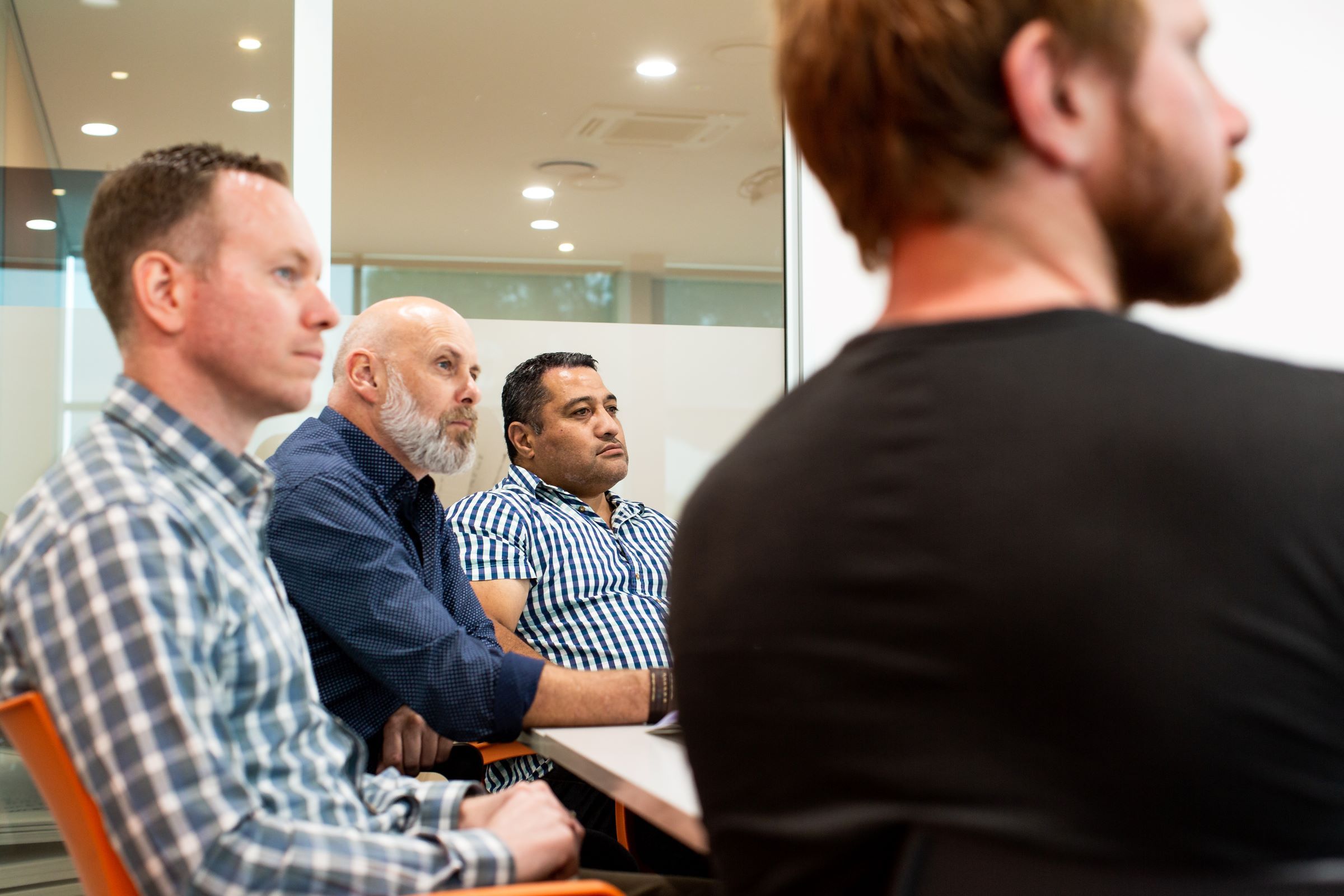 Four peple sitting in NZIM classroom listening to facilitator