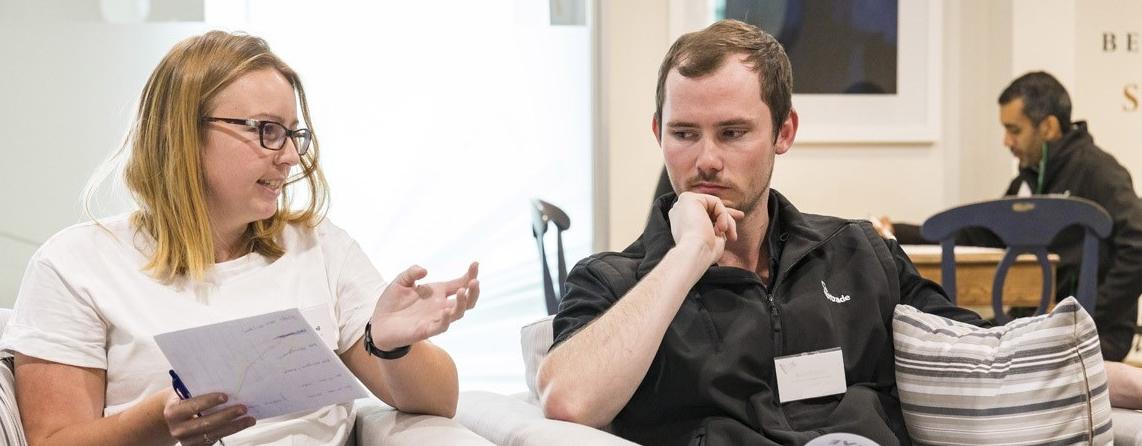 A man and woman, both seated, discussing leadership