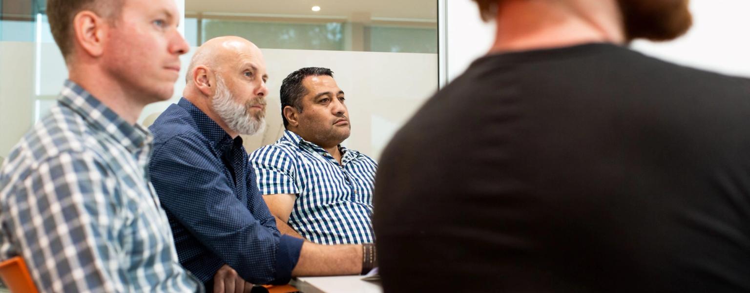 Four peple sitting in NZIM classroom listening to facilitator