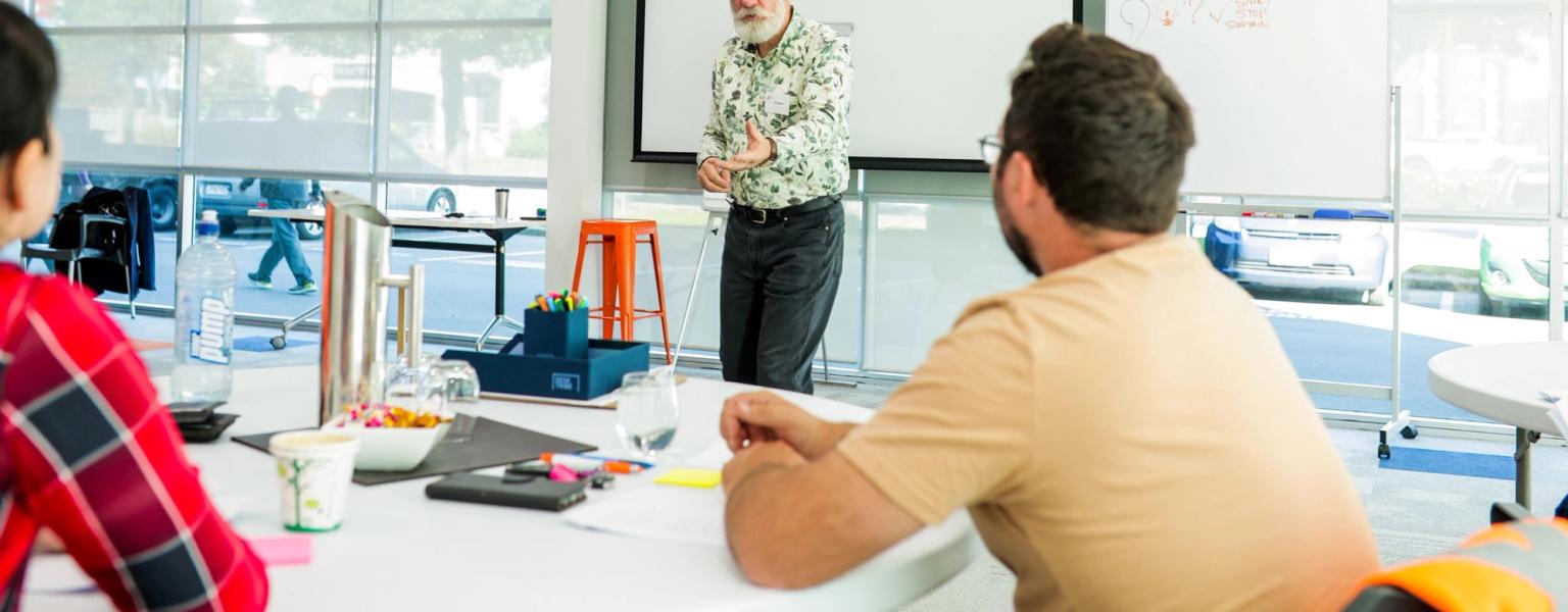 Male facilitator reaching out to class participants as he makes a point