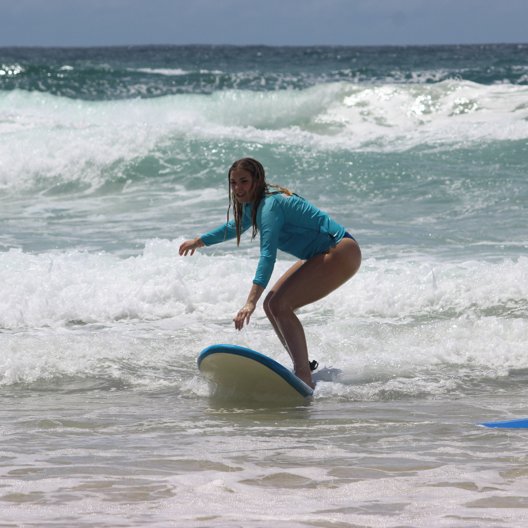Beginner surfer girl catching a wave