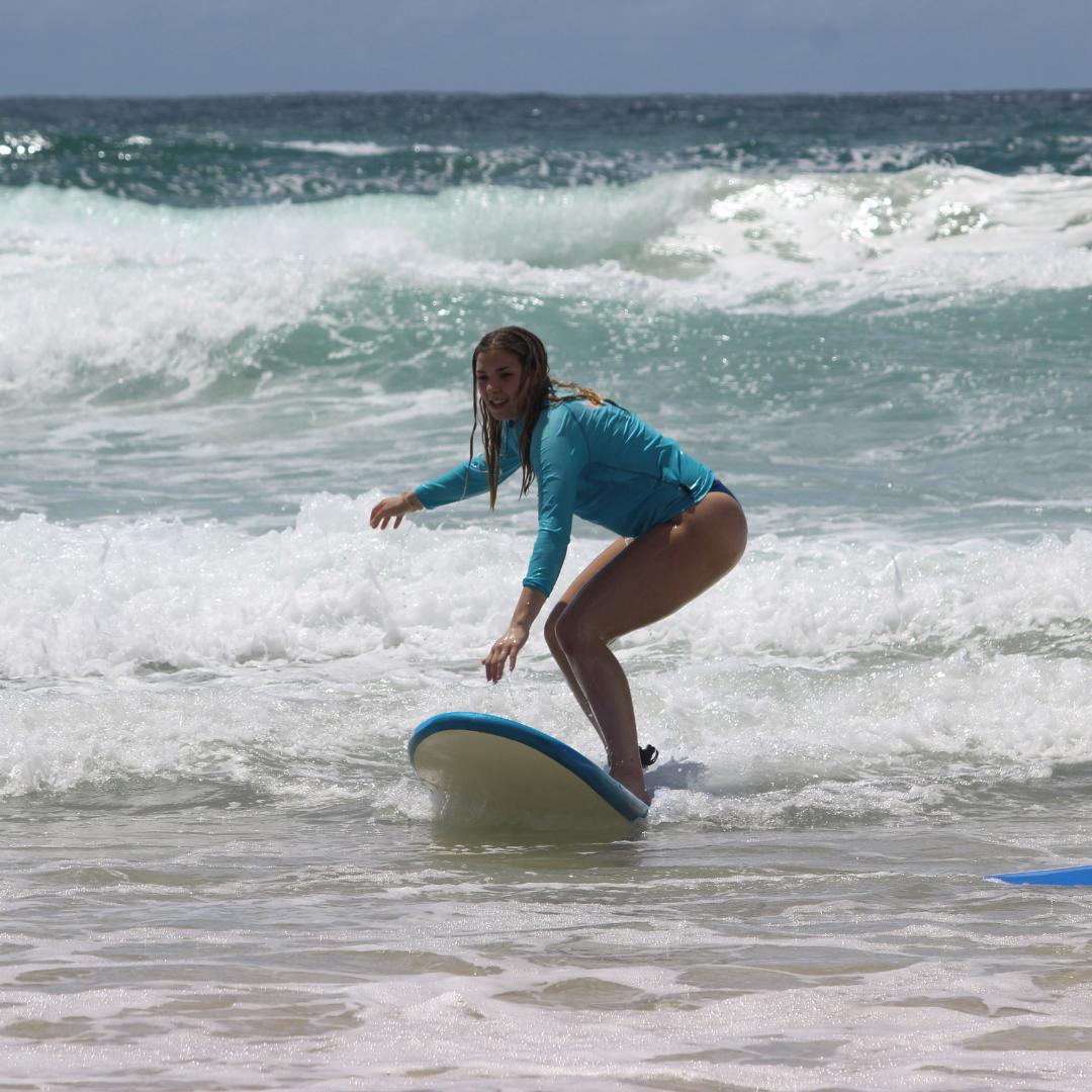 Beginner surfer girl catching a wave