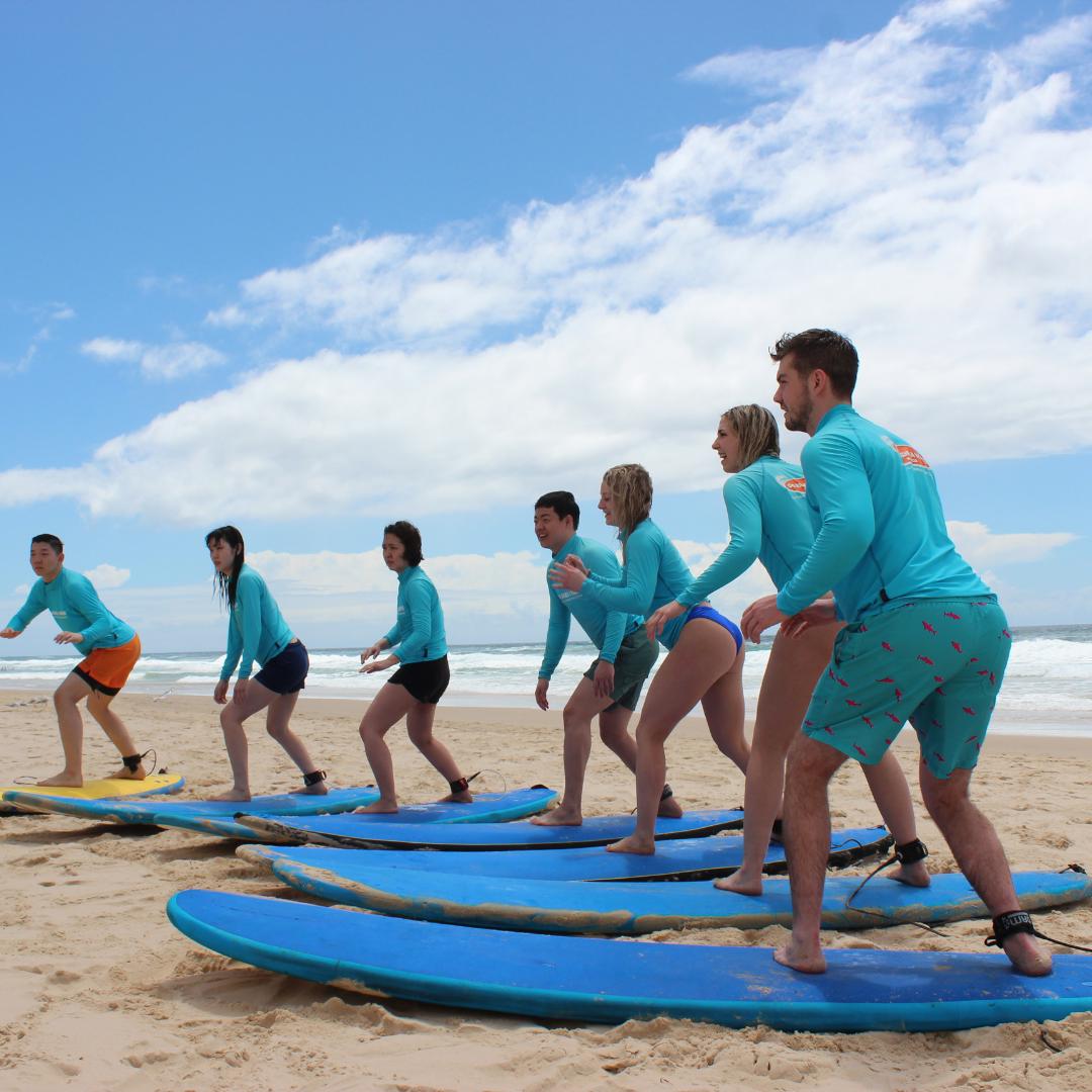 Surf students getting instructions on their surfboards on the beach