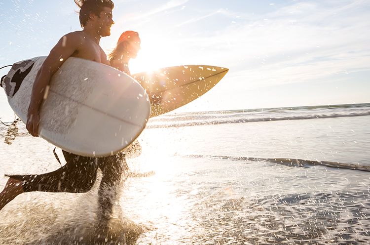 A Man Carrying A Surf Board In The Water