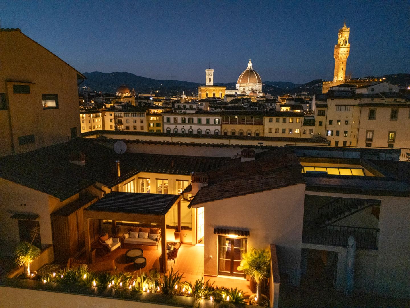 The terrace lit at night with the Duomo and the tower beyond