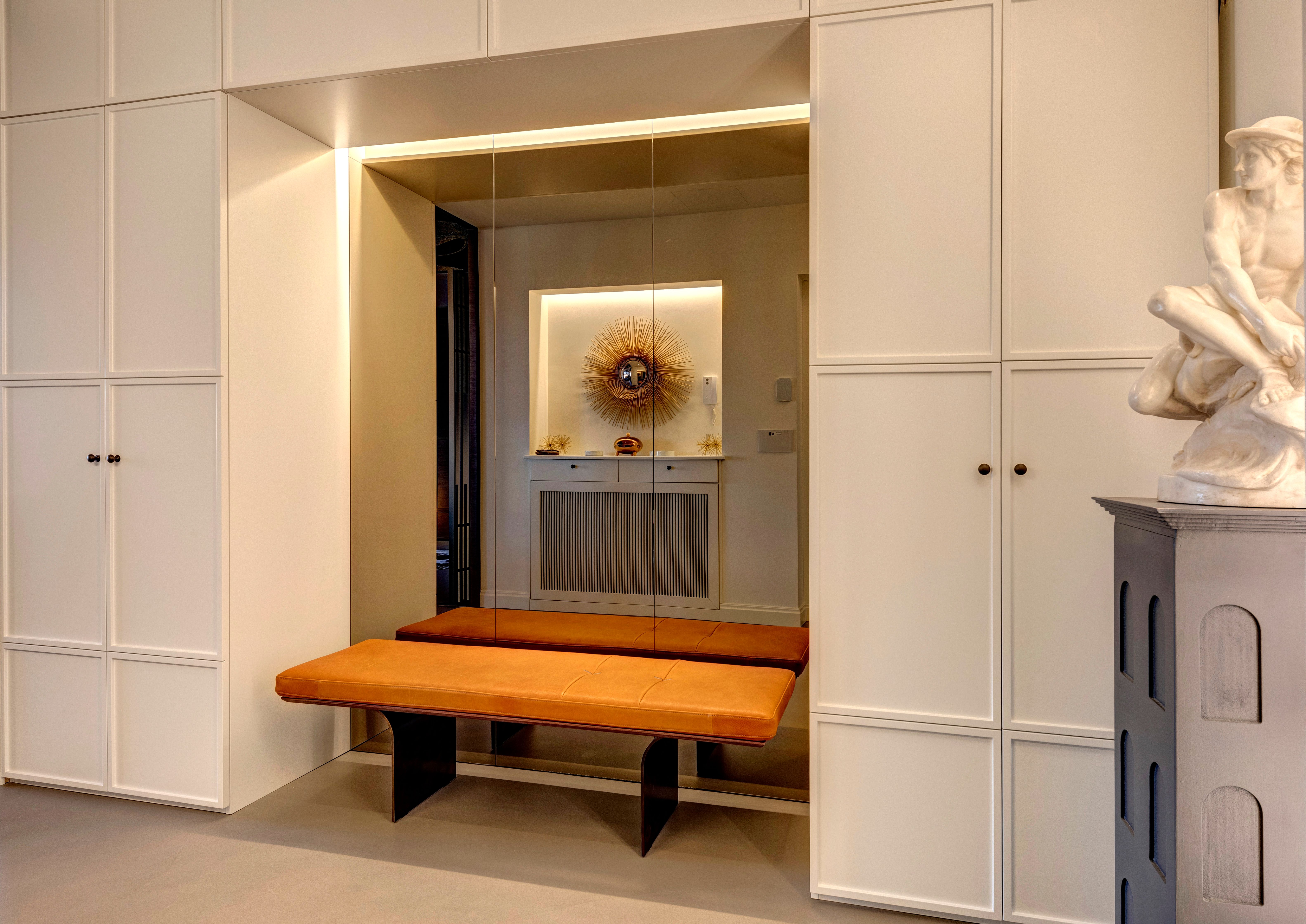 Dressing lobby: an orange leather bench in a lit recess between wardrobes