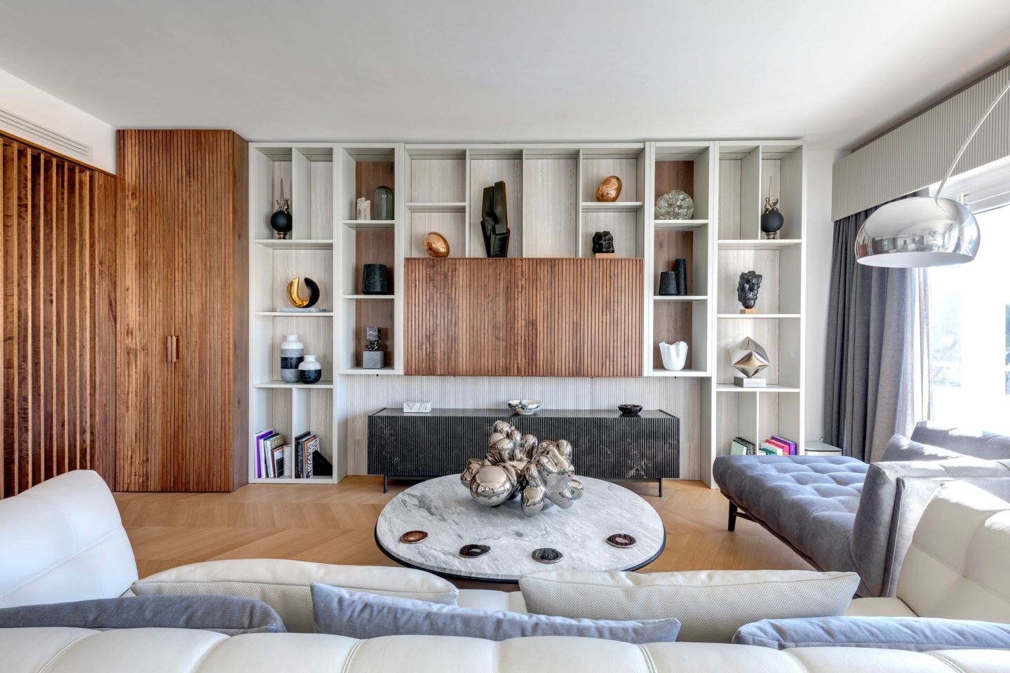 The joinery wall: ribbed walnut, open niches and a stone sideboard