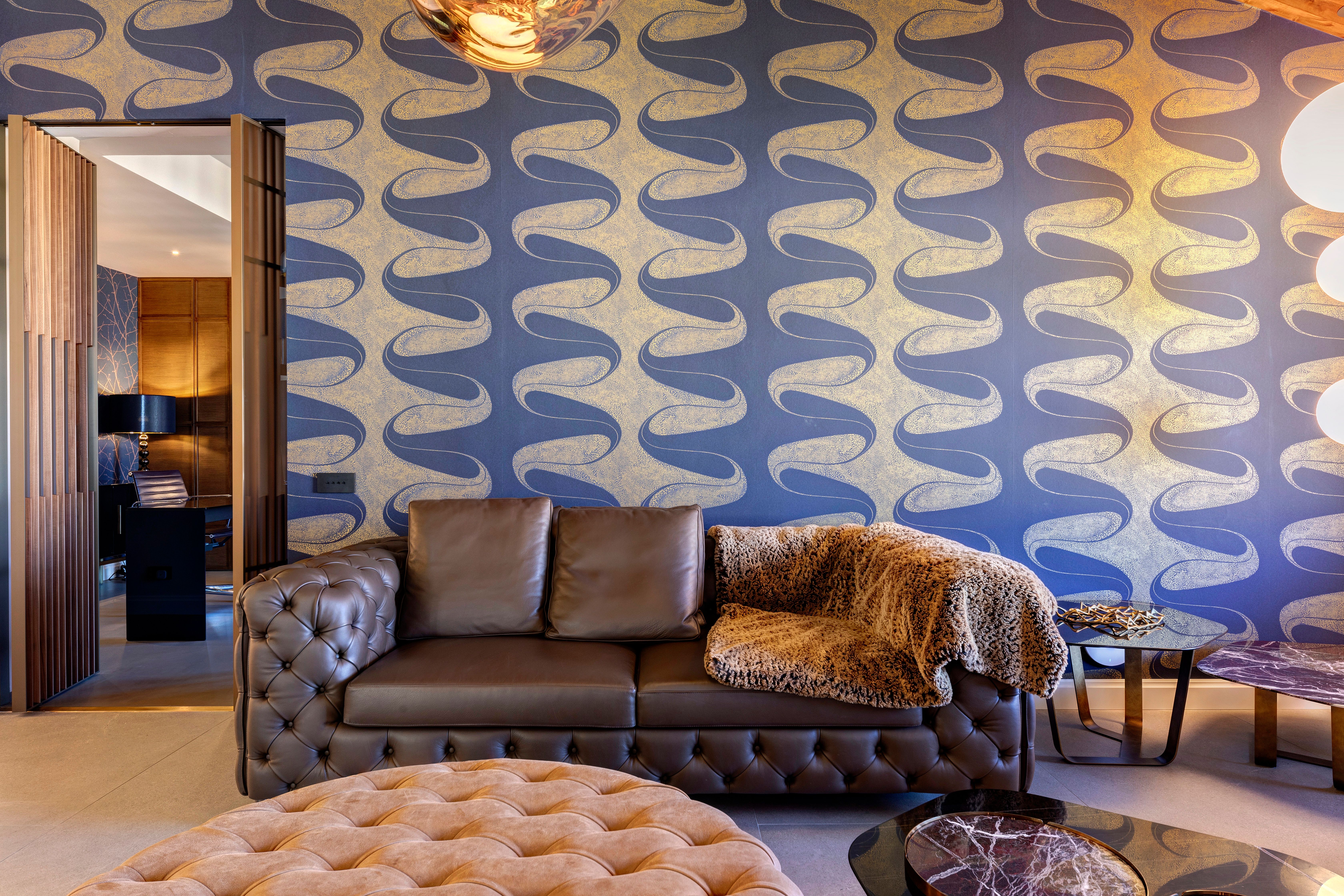 Chesterfield sofas and a tufted ottoman against the patterned wall
