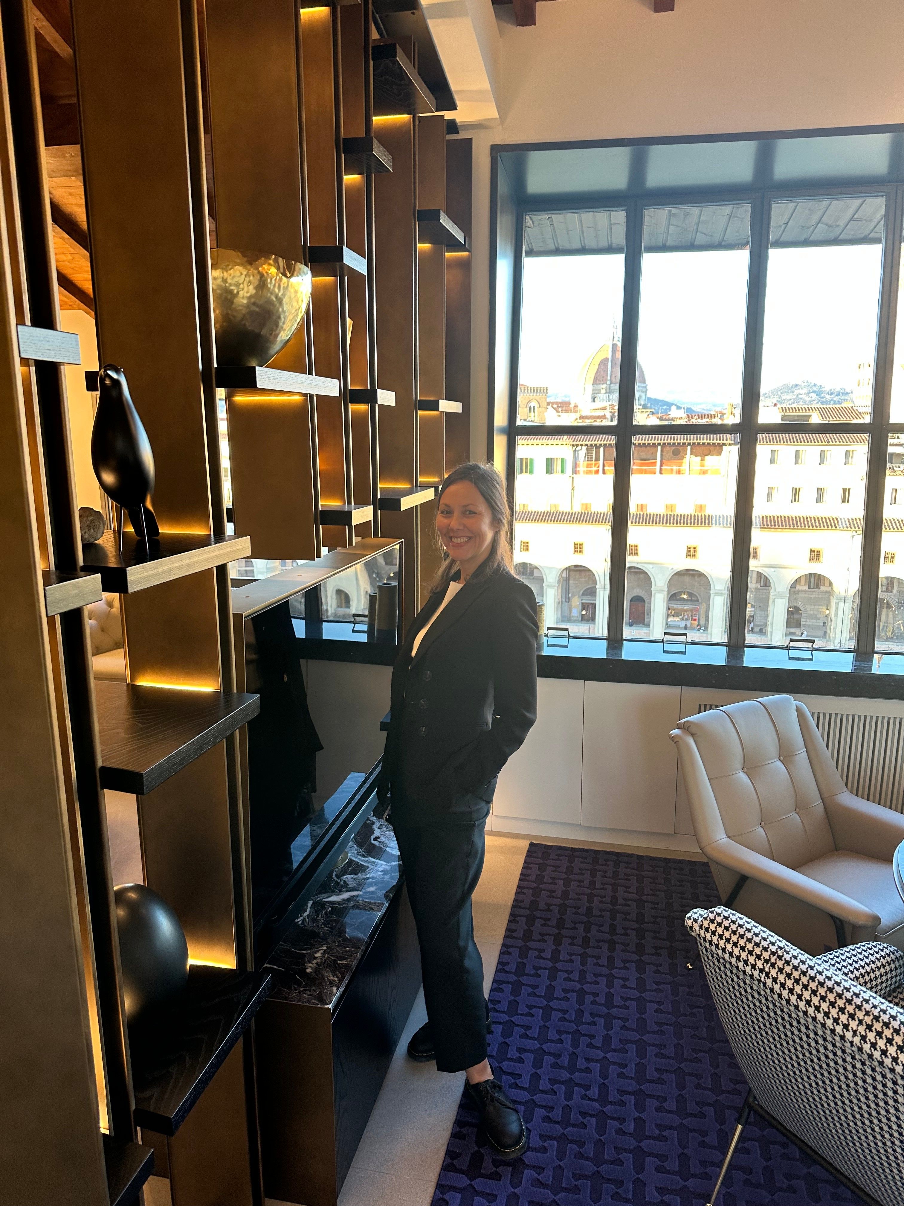 Deniz Önel accanto alla libreria che ha disegnato per Sky-Line, il Duomo nella finestra alle sue spalle