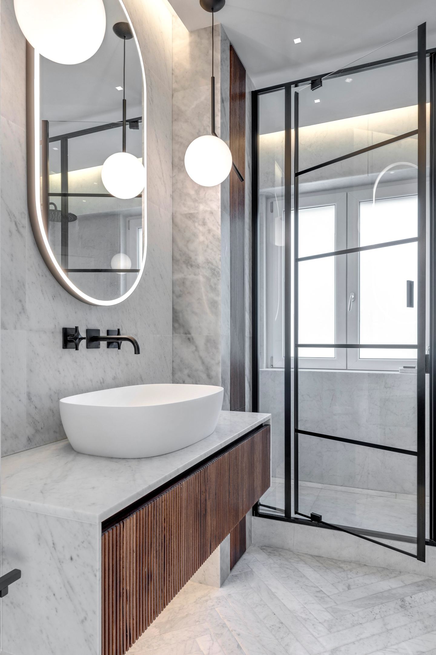 Oval mirror and globe lights above the walnut vanity