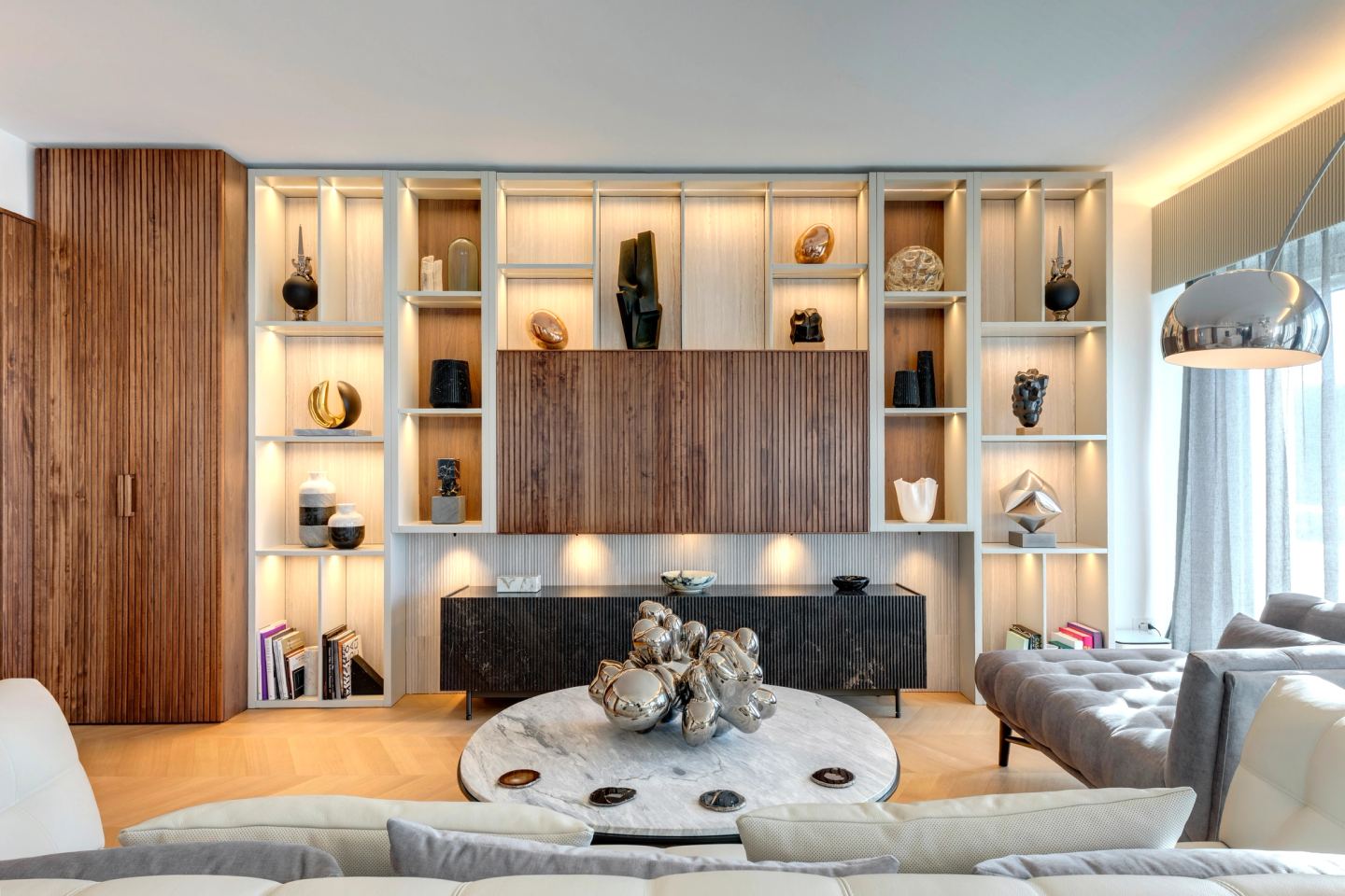 The joinery wall lit from within its niches, evening