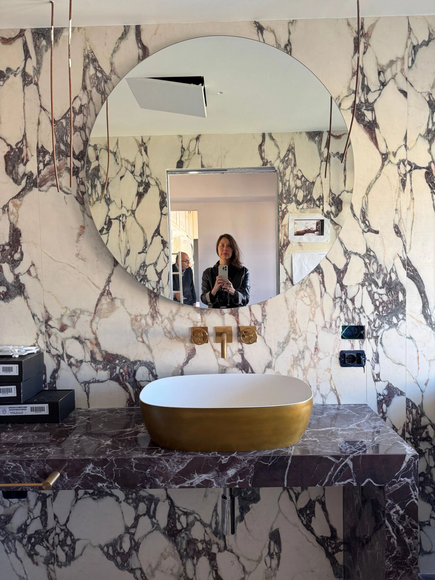 The round mirror above the gold basin