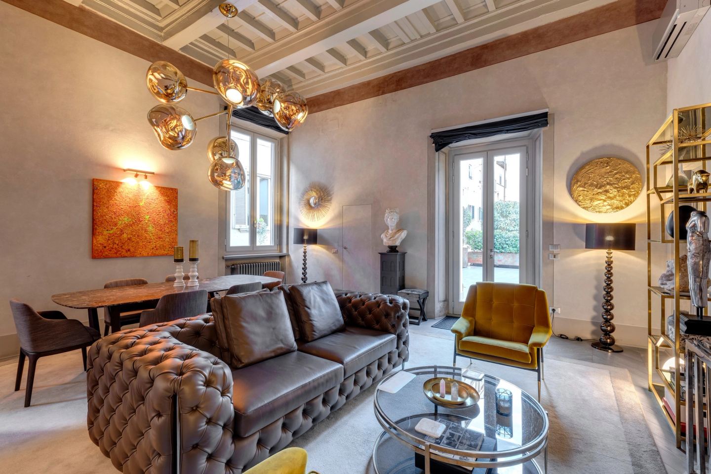 The sofa and the dining table under the coffered ceiling, a wall light over an orange painting