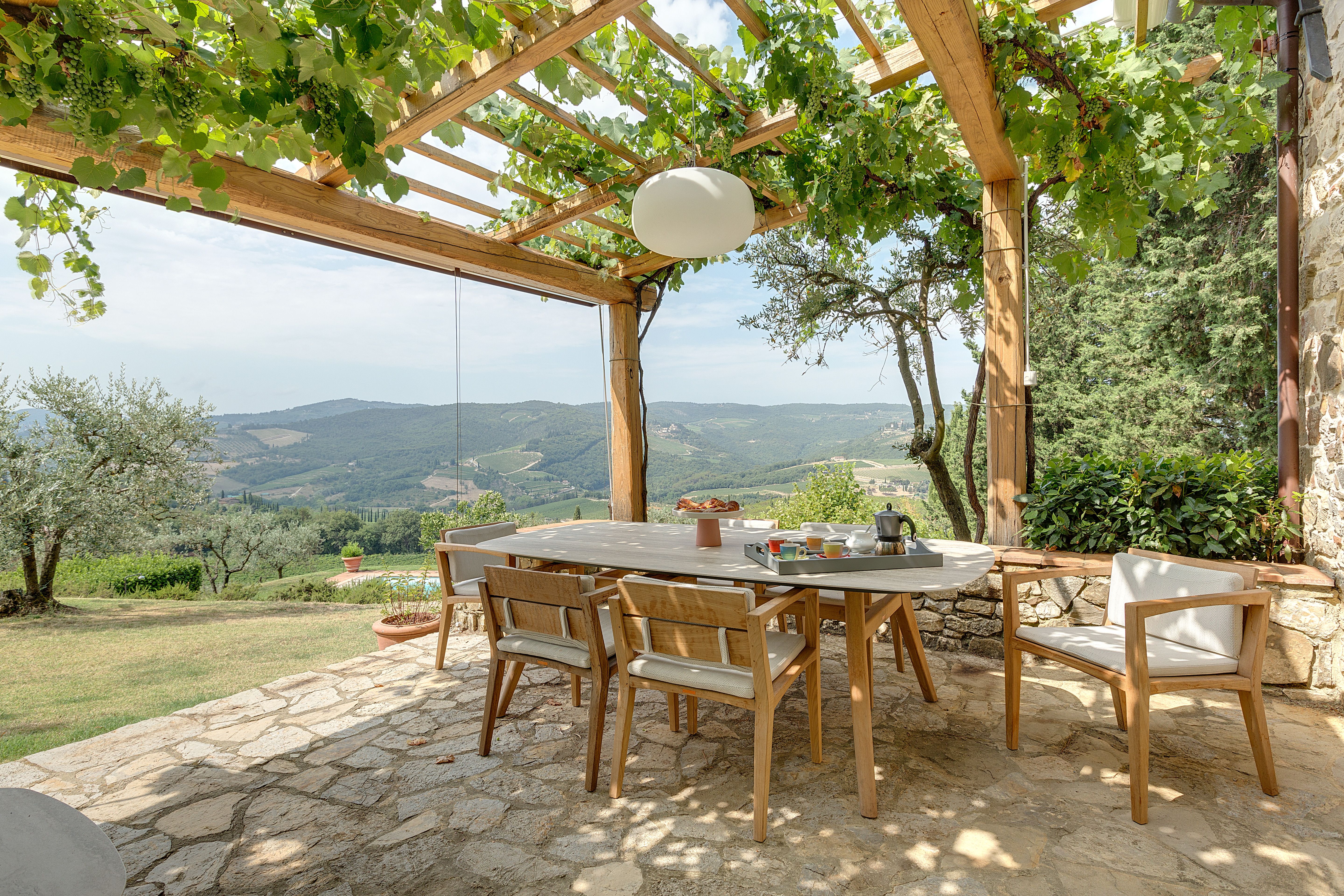 Il tavolo lungo apparecchiato sotto la pergola in legno
