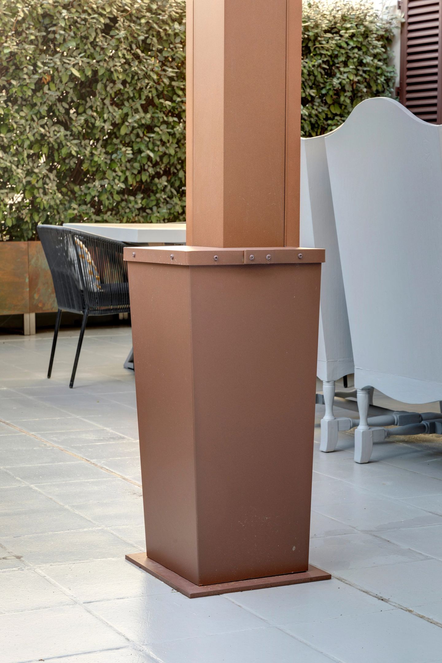 Un peso in corten ai piedi di una colonna della pergola