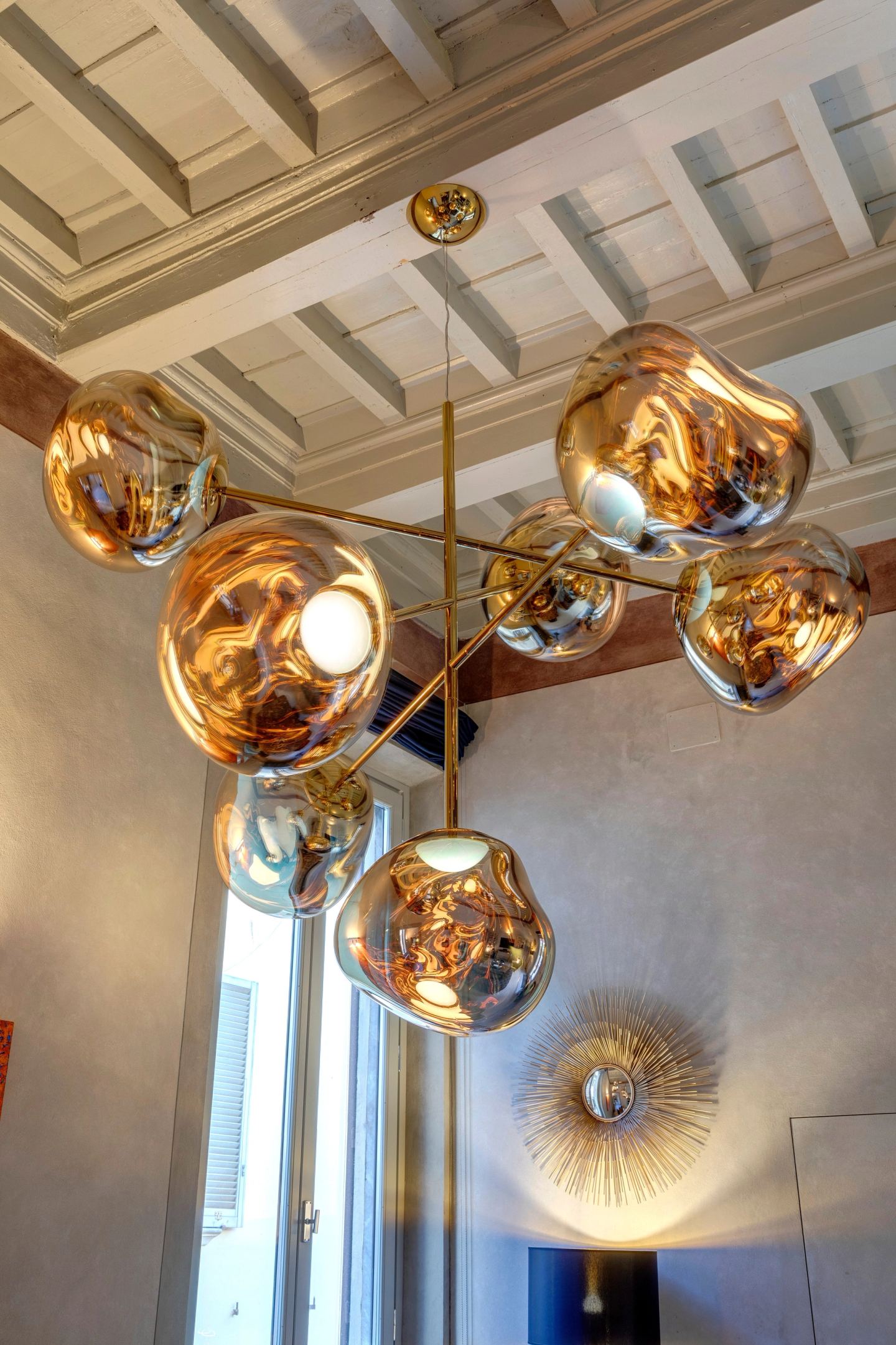 The chandelier's molten-glass globes, a sunburst wall light below