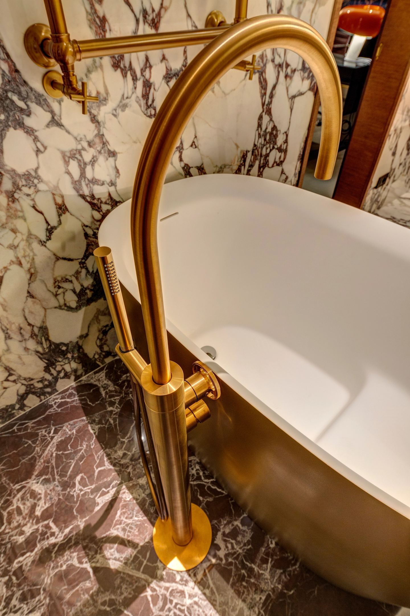 The brass bath at night against the veined marble