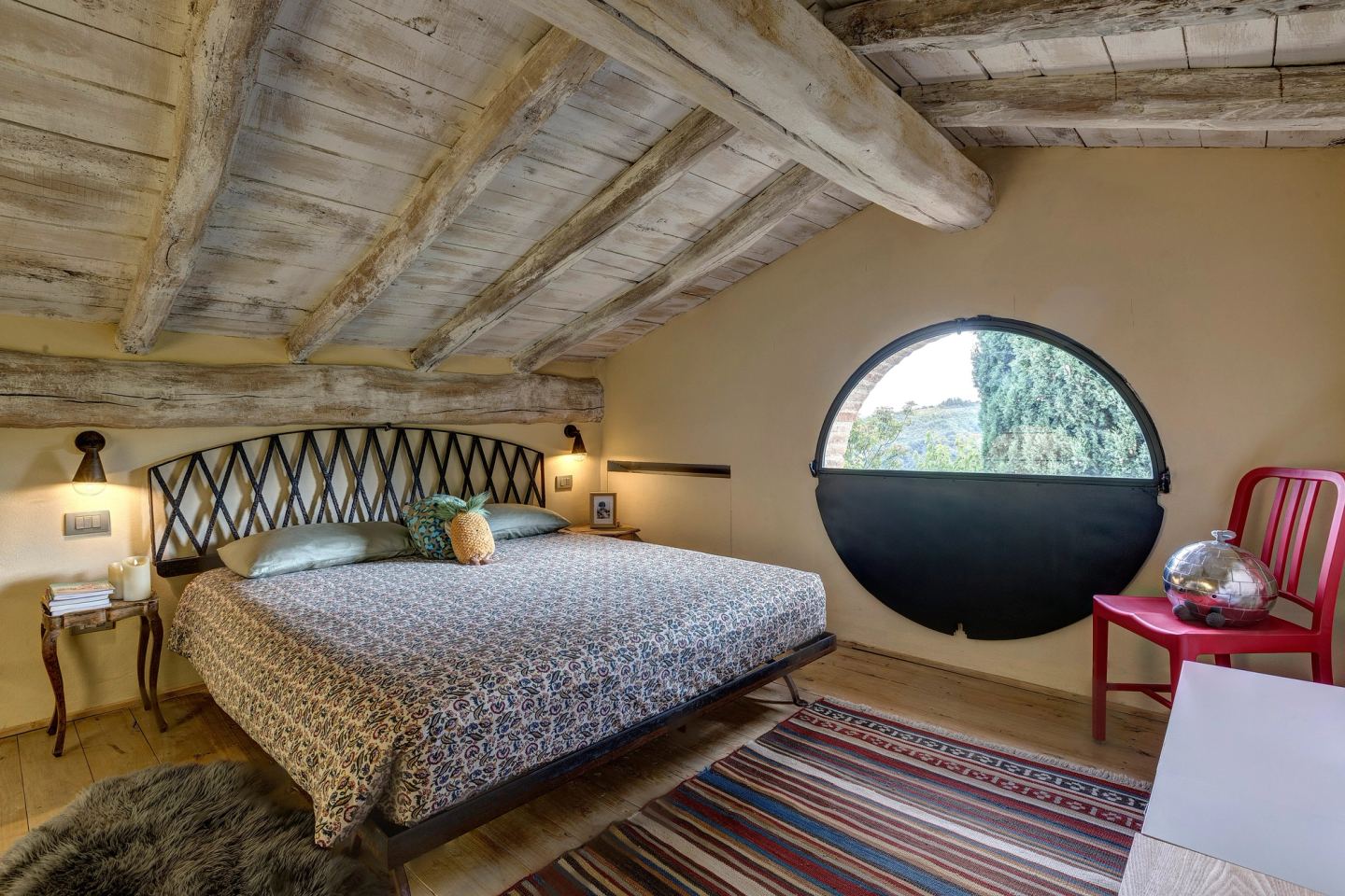 The mezzanine bed under the beams, the round window beside it