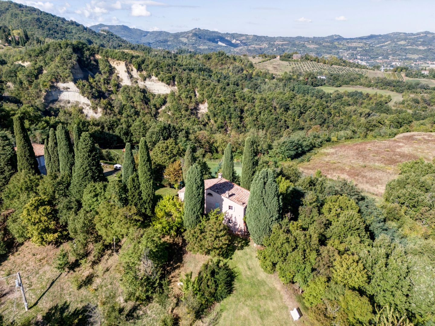 Il versante boscoso, la casa tra i suoi cipressi