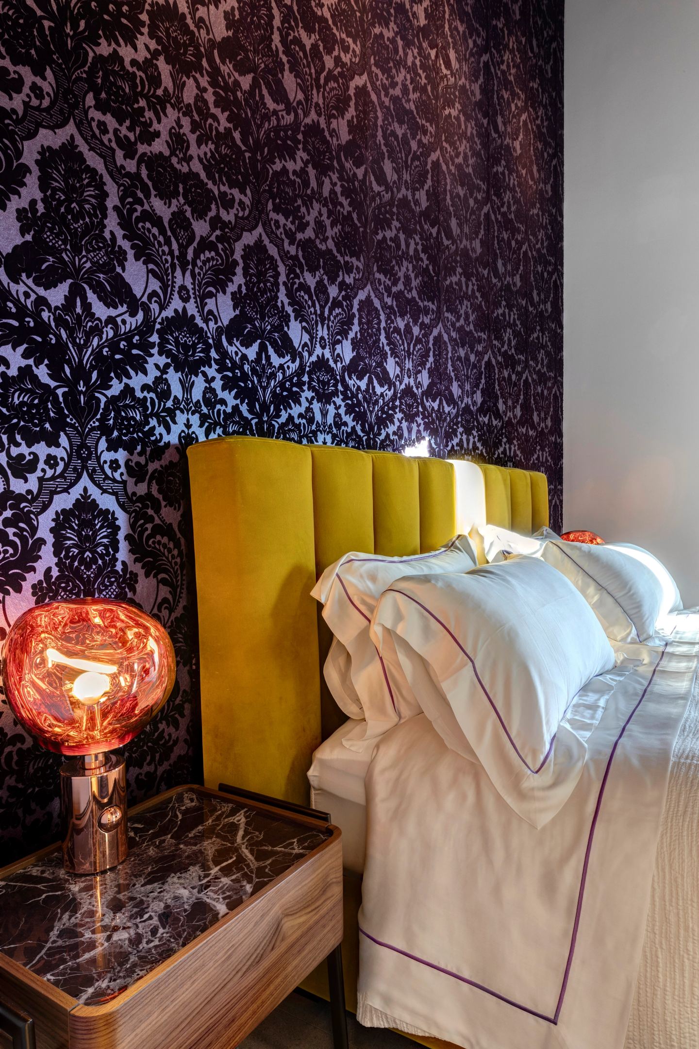 Red glass bedside lamp against the yellow headboard