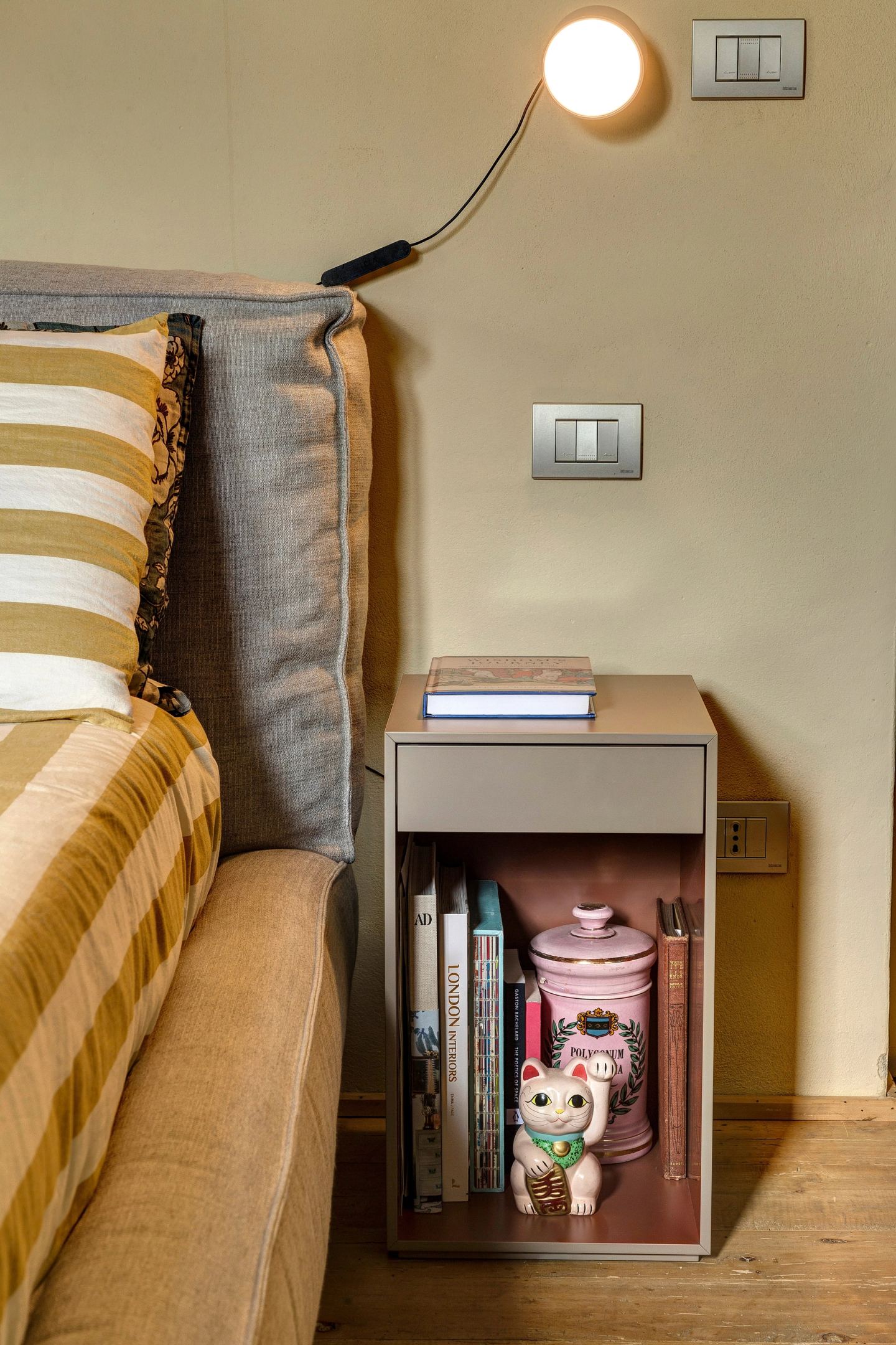 A bedside table in a contrasting colour, its reading light above