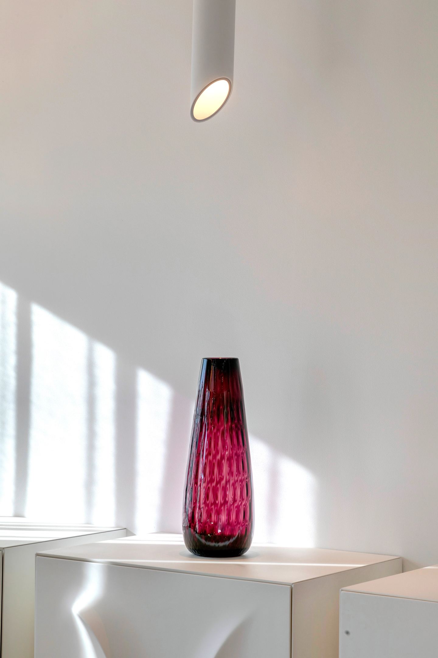Single coloured glass vase in a shaft of daylight