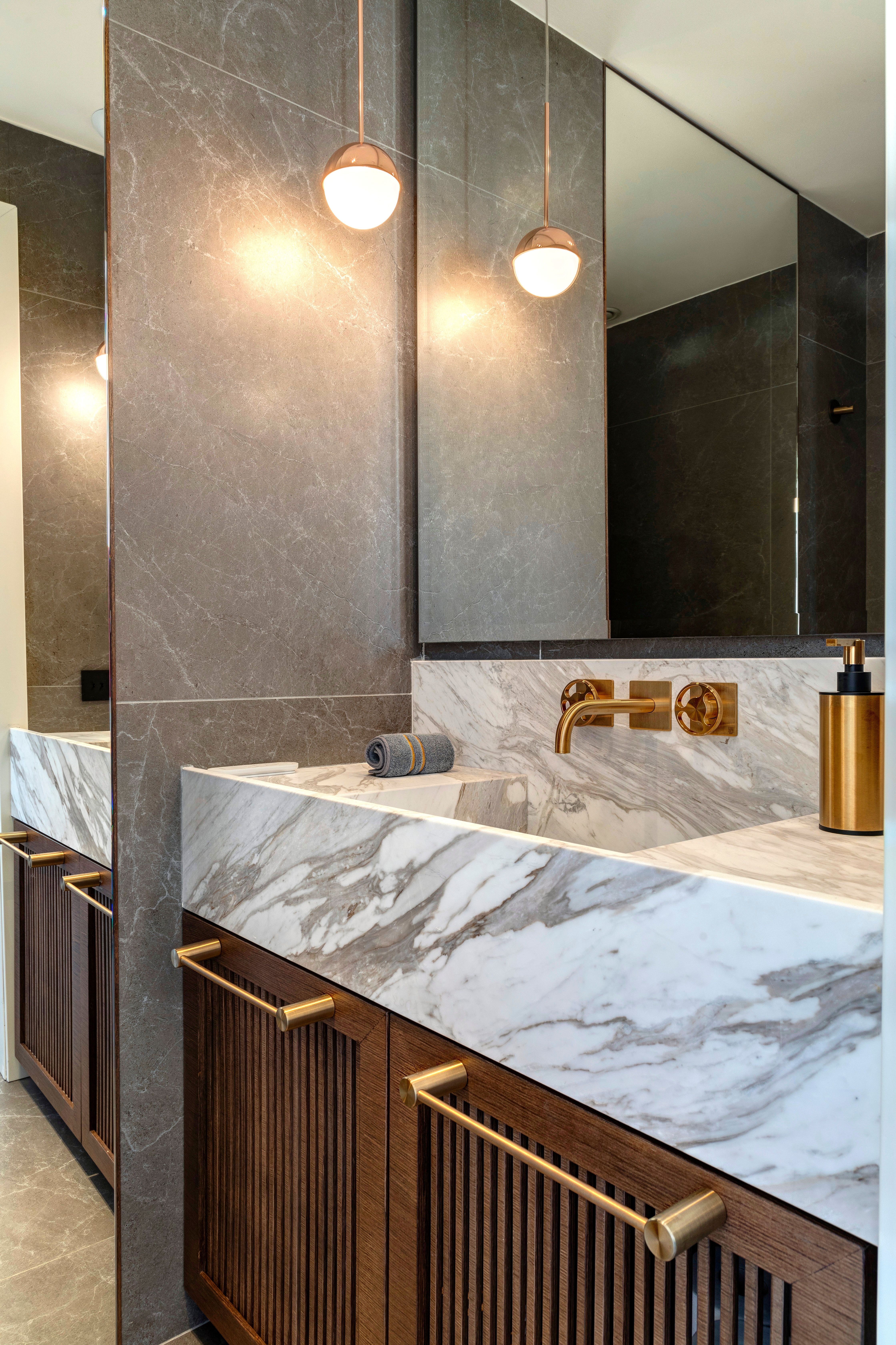 The guest WC: white marble top over fluted wood, brass taps