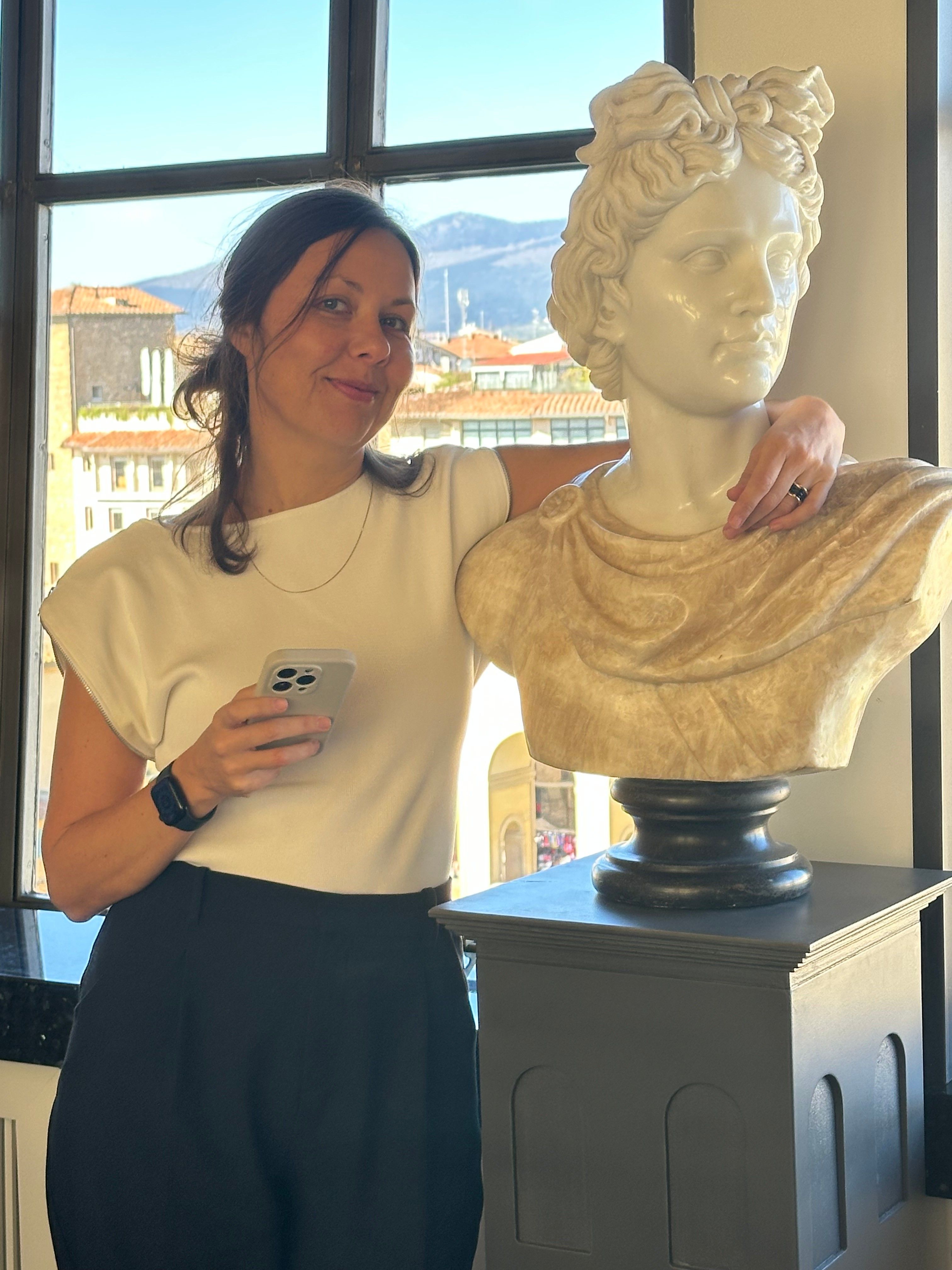 Deniz Önel at a window over Florence, one arm resting on a marble bust