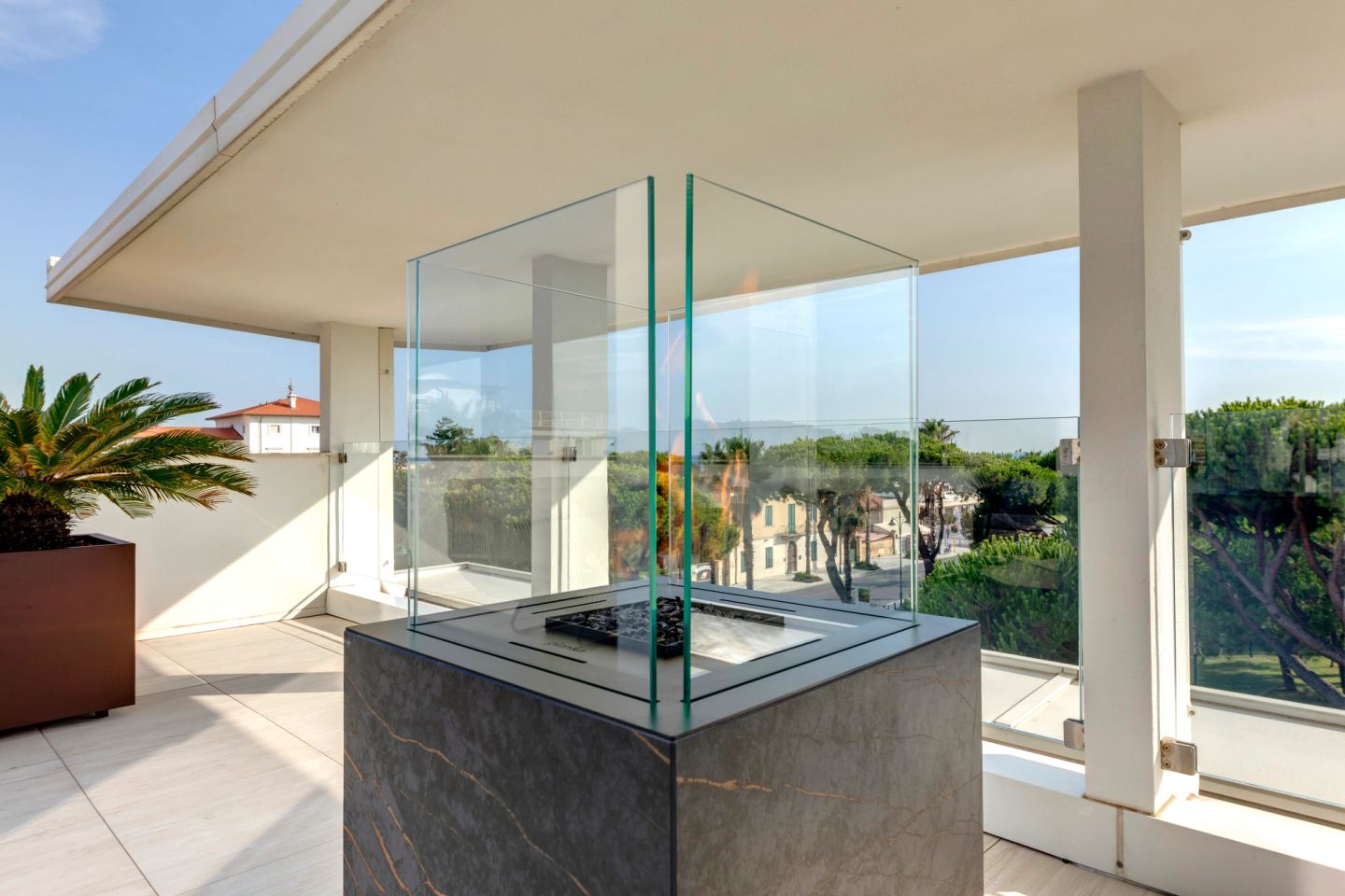 A fire column in veined marble inside its frameless glass