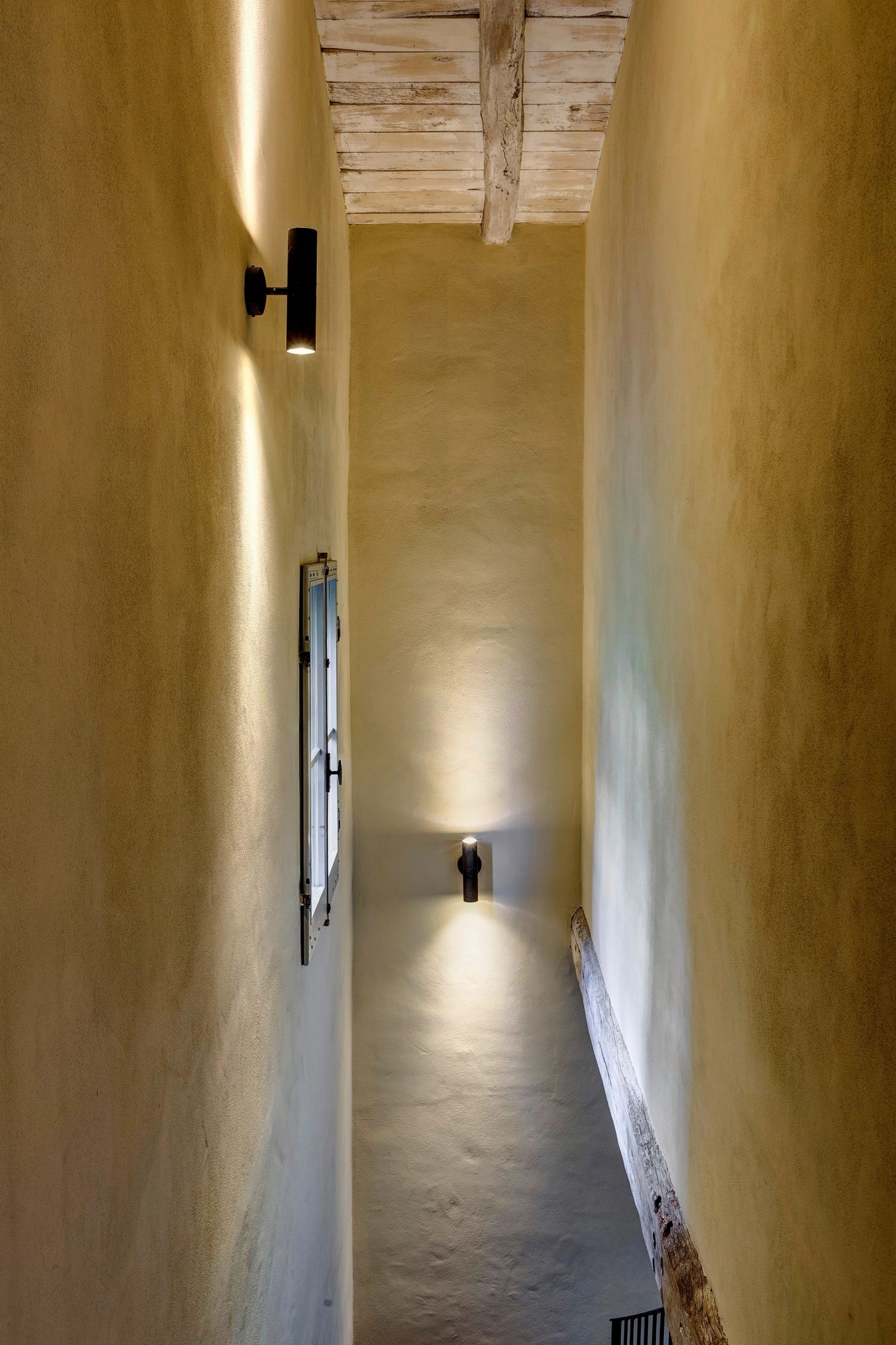 A wall light on the warm plaster of the corridor
