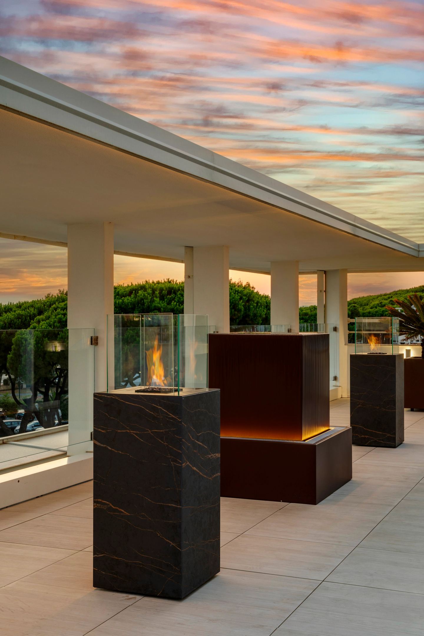 The three sculptures unlit under a pink sky