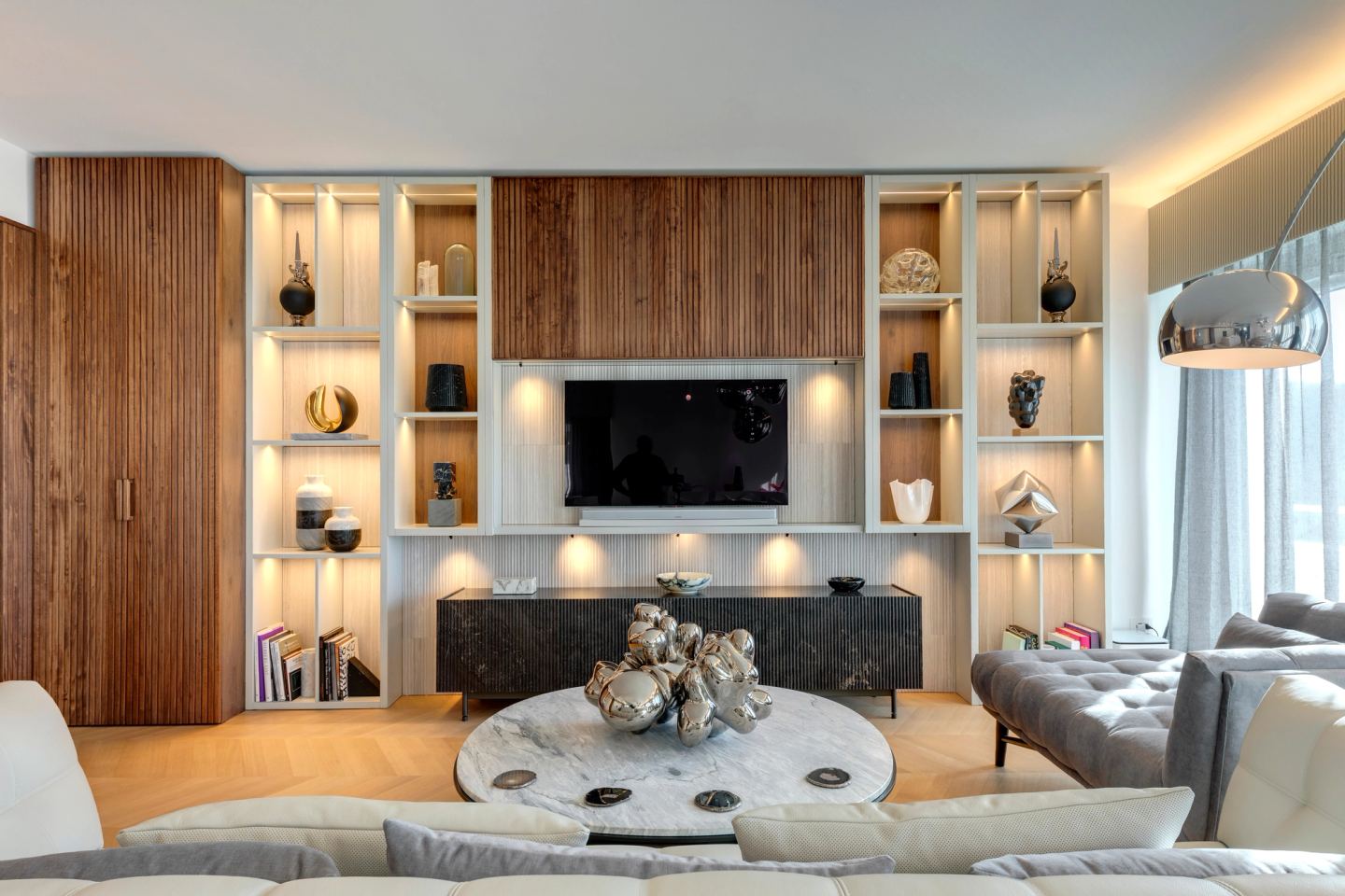 Living room by lamplight, the stone sideboard grounding the wall