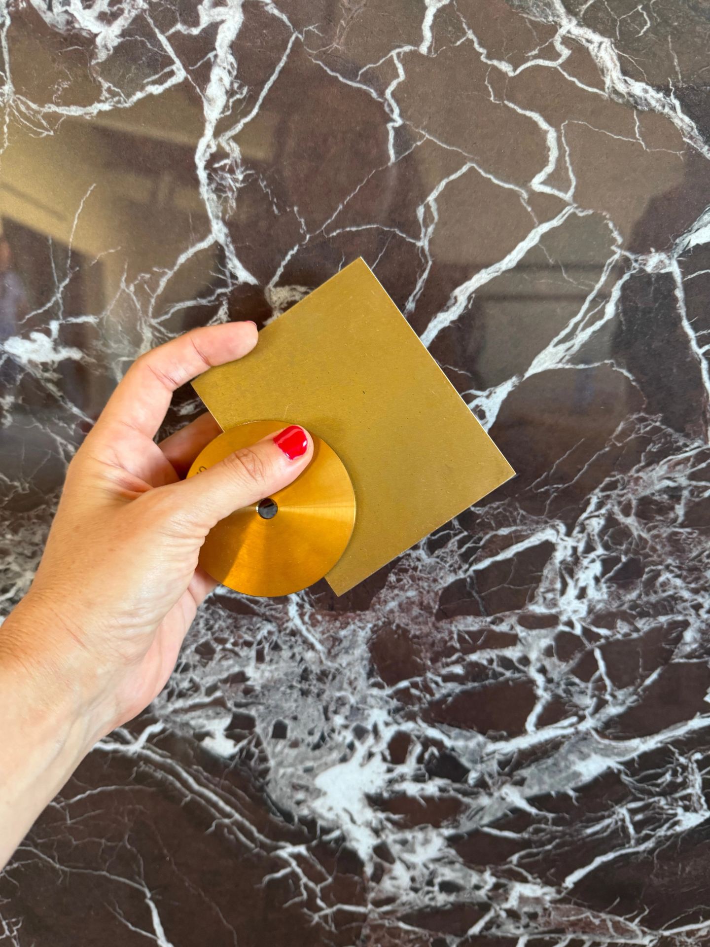 A brass sample laid on dark veined marble