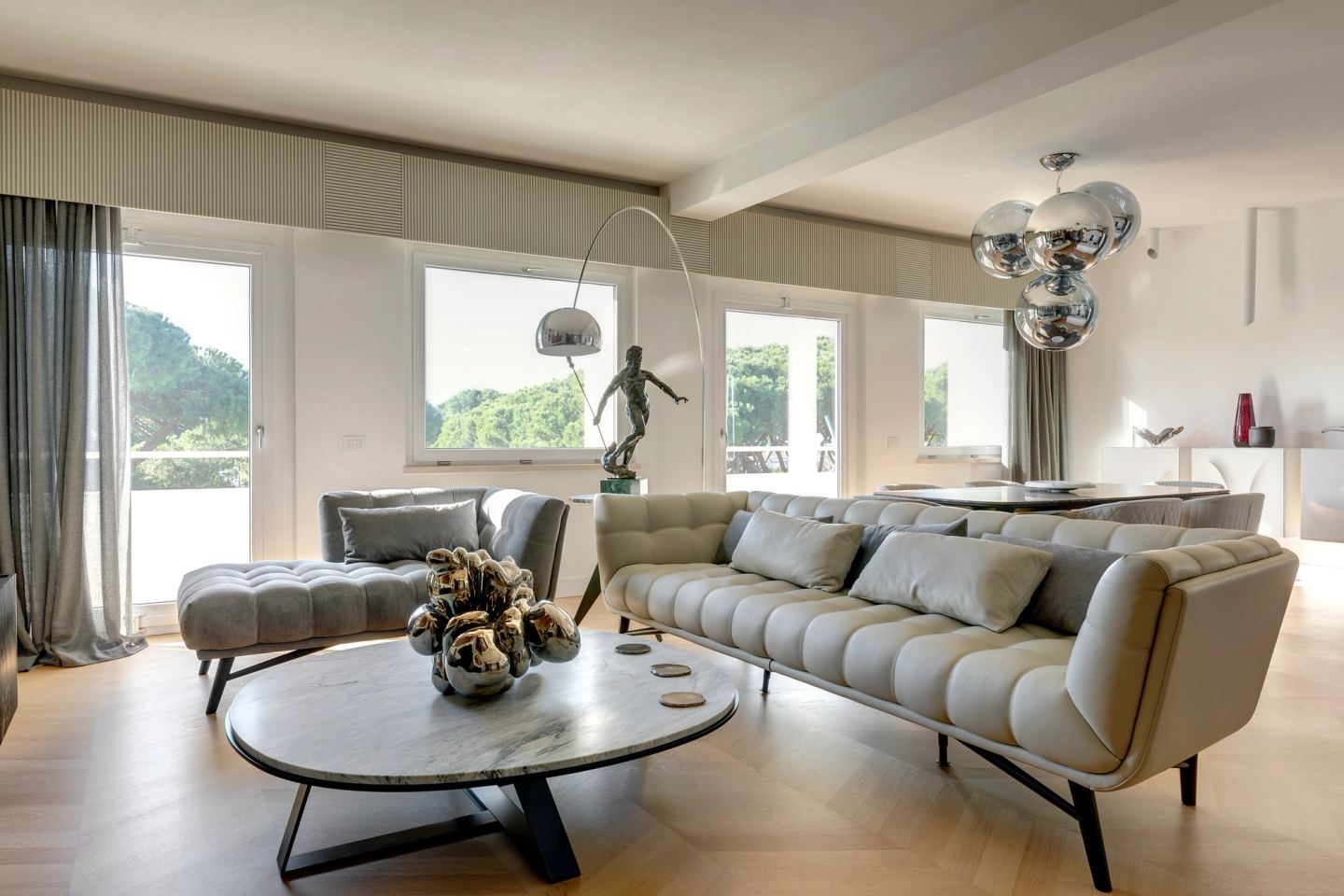Low sofa and marble table beneath the arc lamp, bronze figure on the sideboard