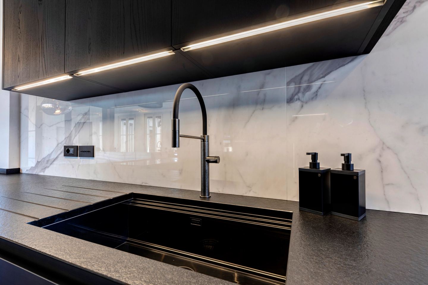 Black stone sink below the marble, a linear light across the ceiling