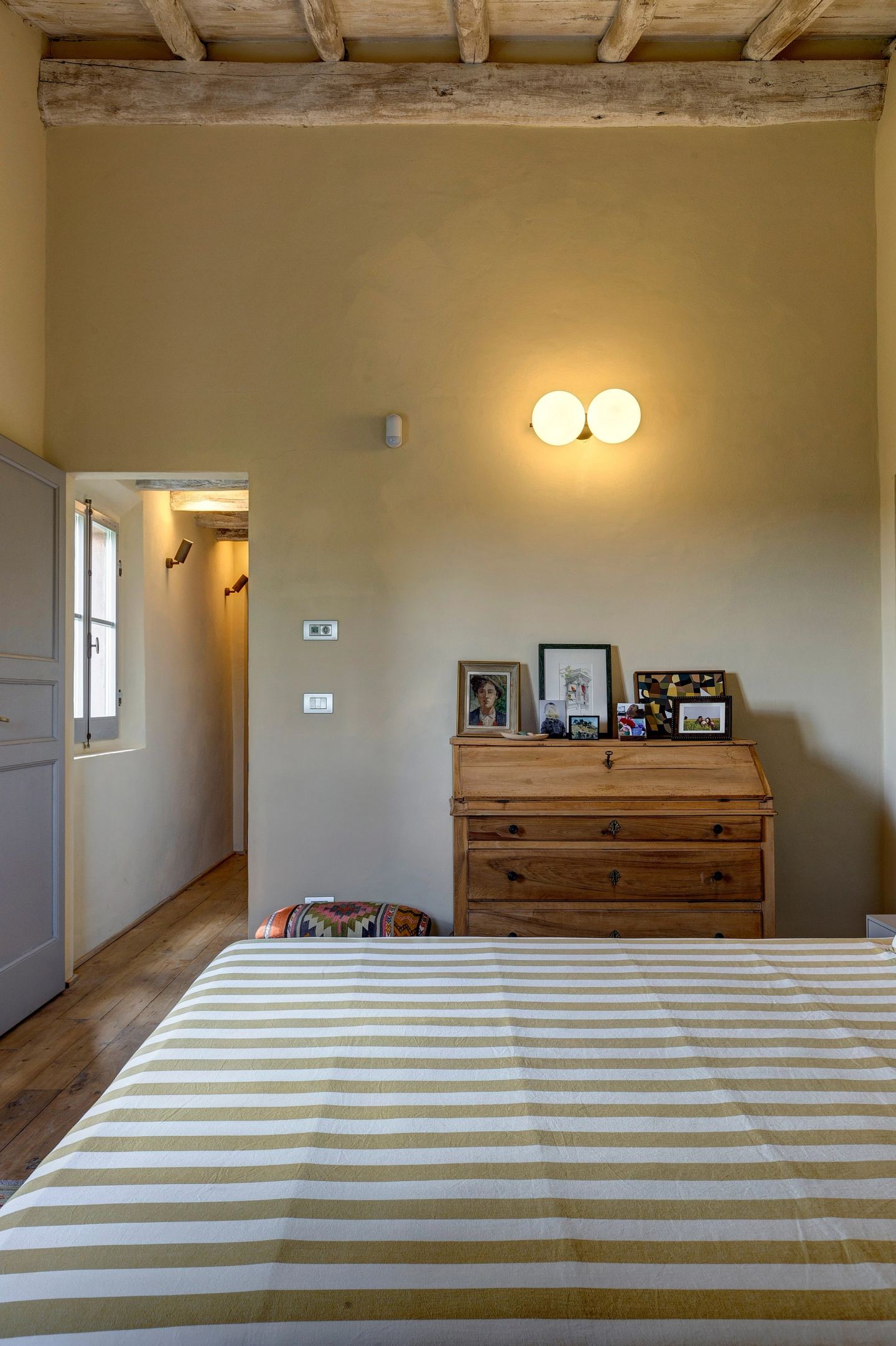 The secretaire and the wall light at the foot of the bed