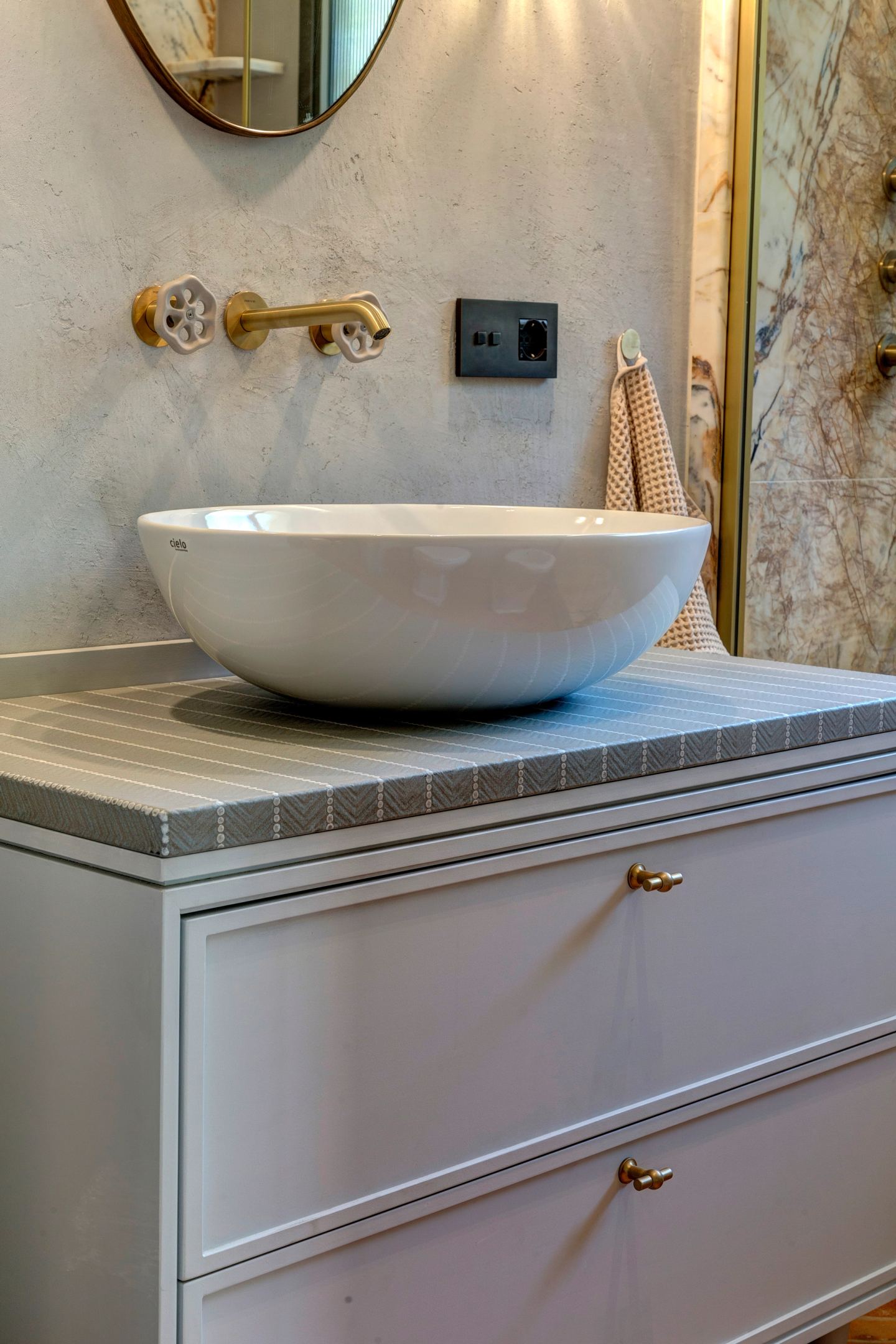 The basin on its tiled plinth, brass taps behind