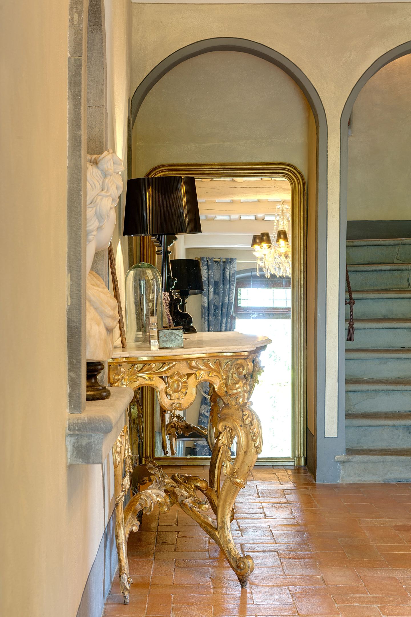 Past the gilt console to the stone steps