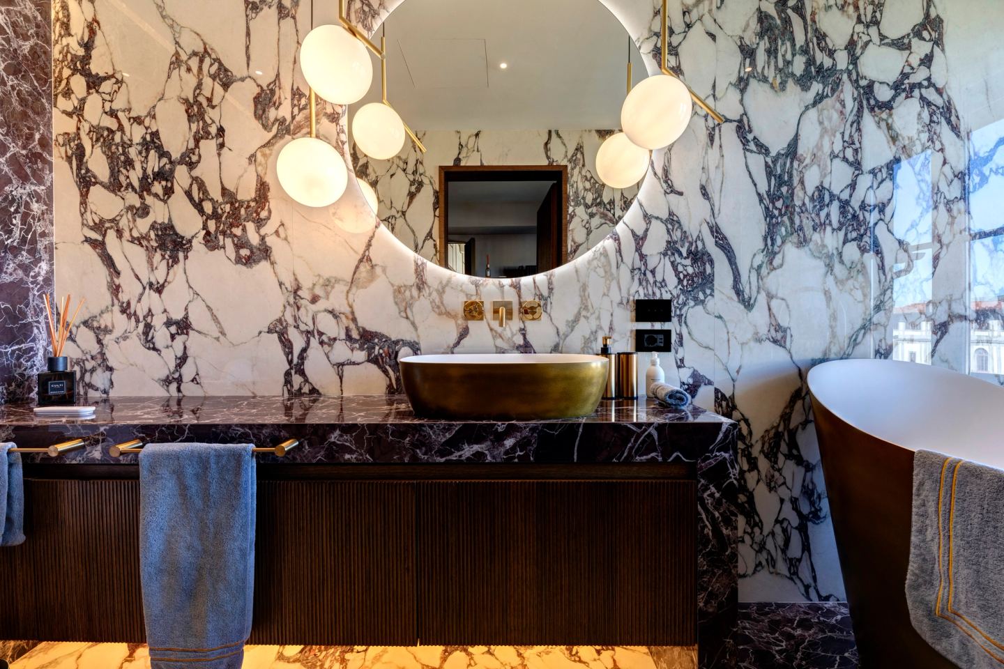 Brass bath and round mirror in the marble bathroom