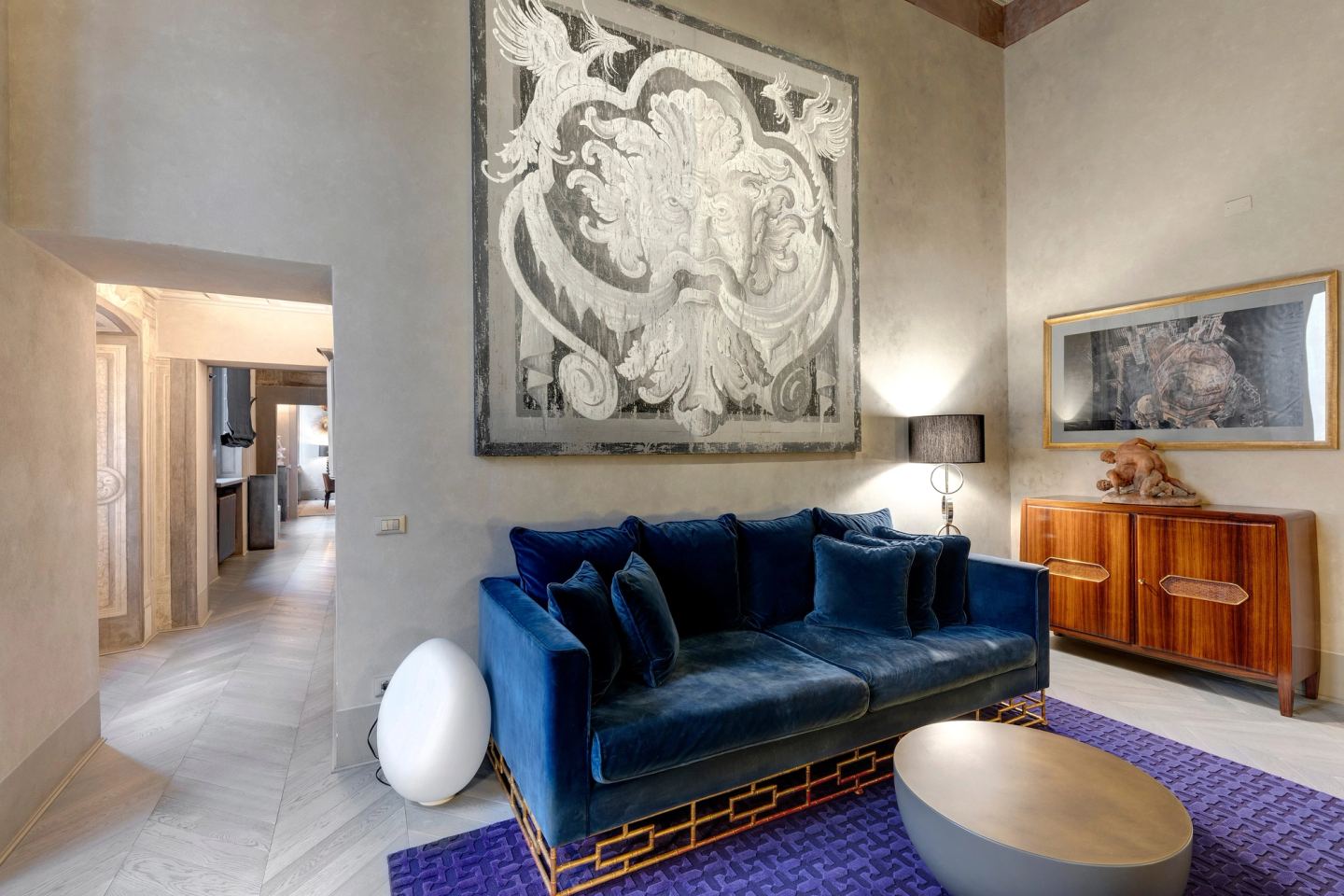 The sitting room towards the corridor, an egg-shaped lamp on the floor beside the sofa