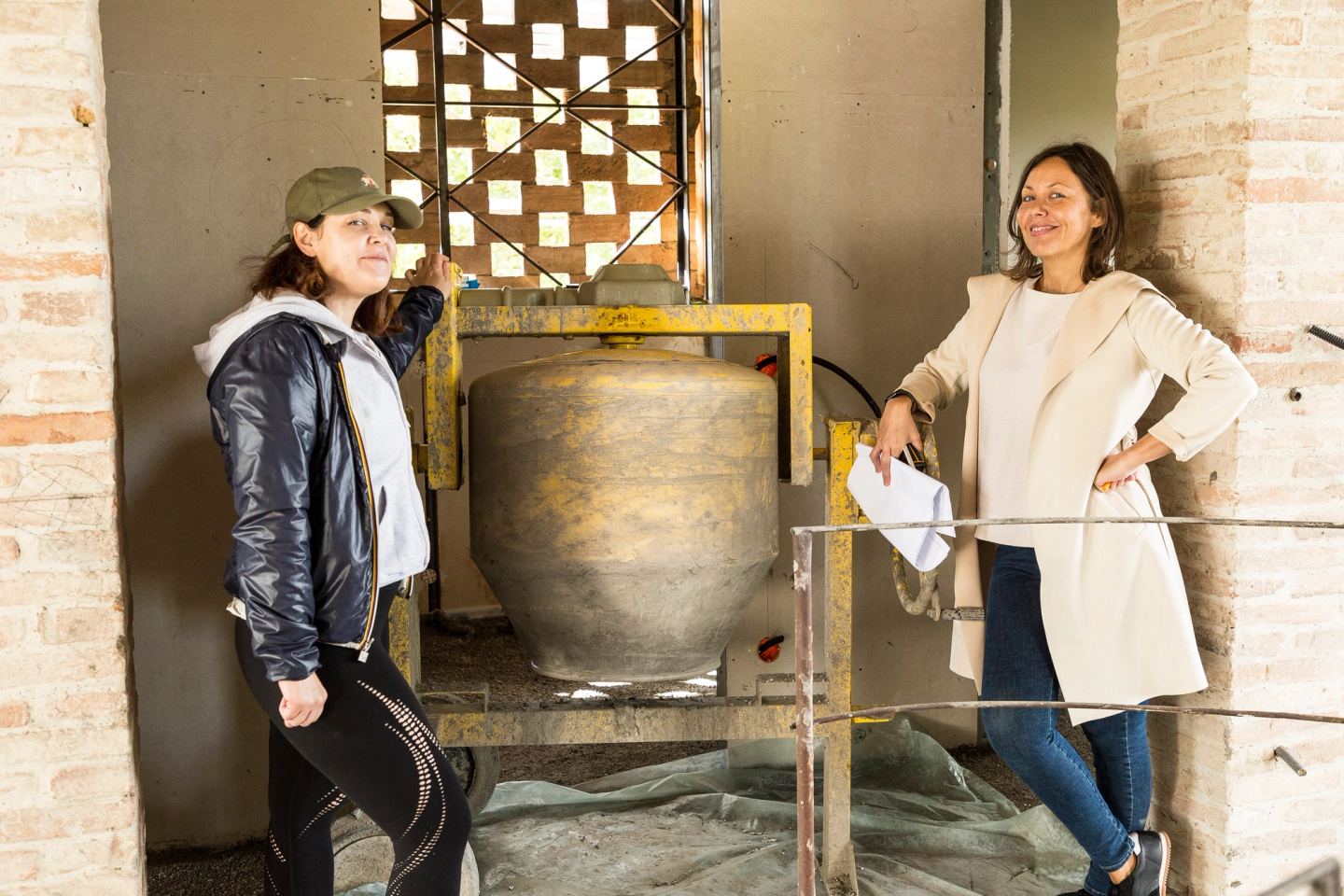 Deniz Önel and Rebecca either side of the large jar, beneath the brick screen