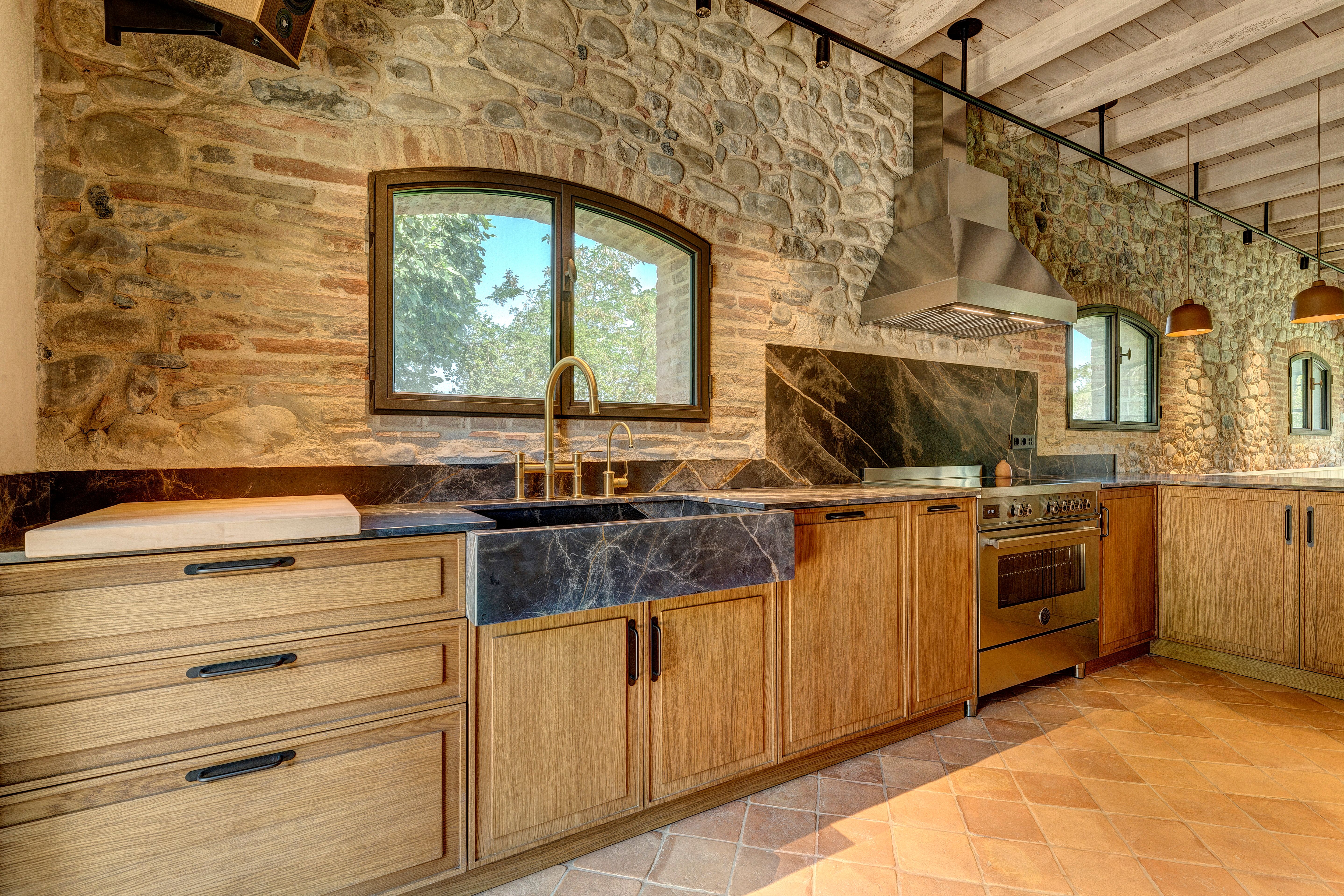 Oak cabinetry and dark marble under the arched window