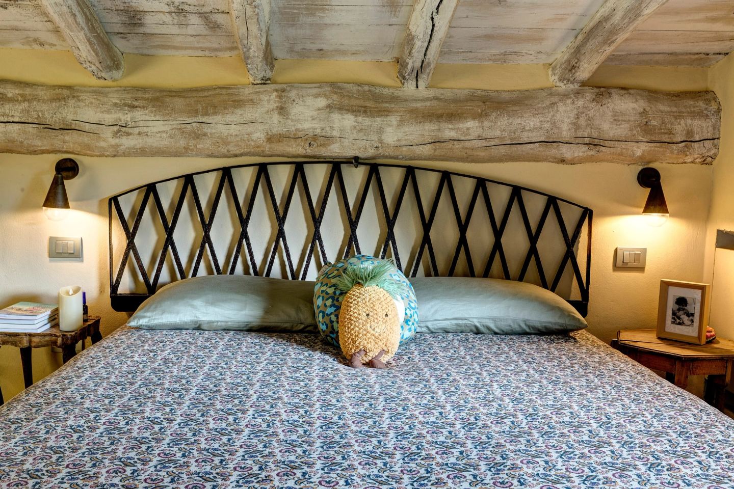 The bed's iron lattice headboard between two wall lamps