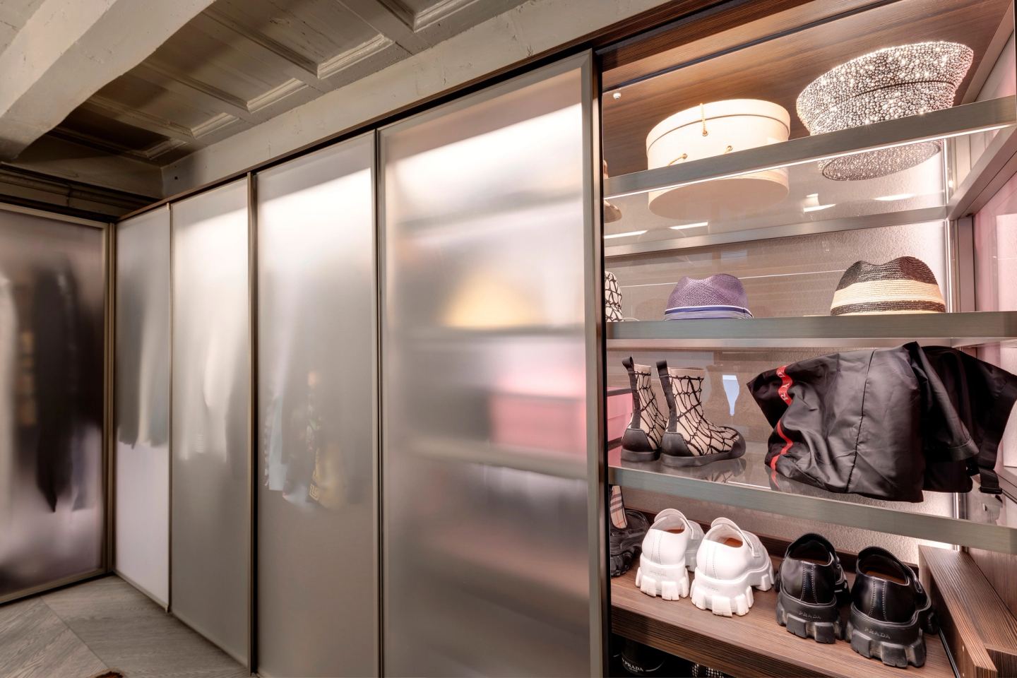 The closet room: etched-glass doors, one open on lit shelves of hats, bags and shoes
