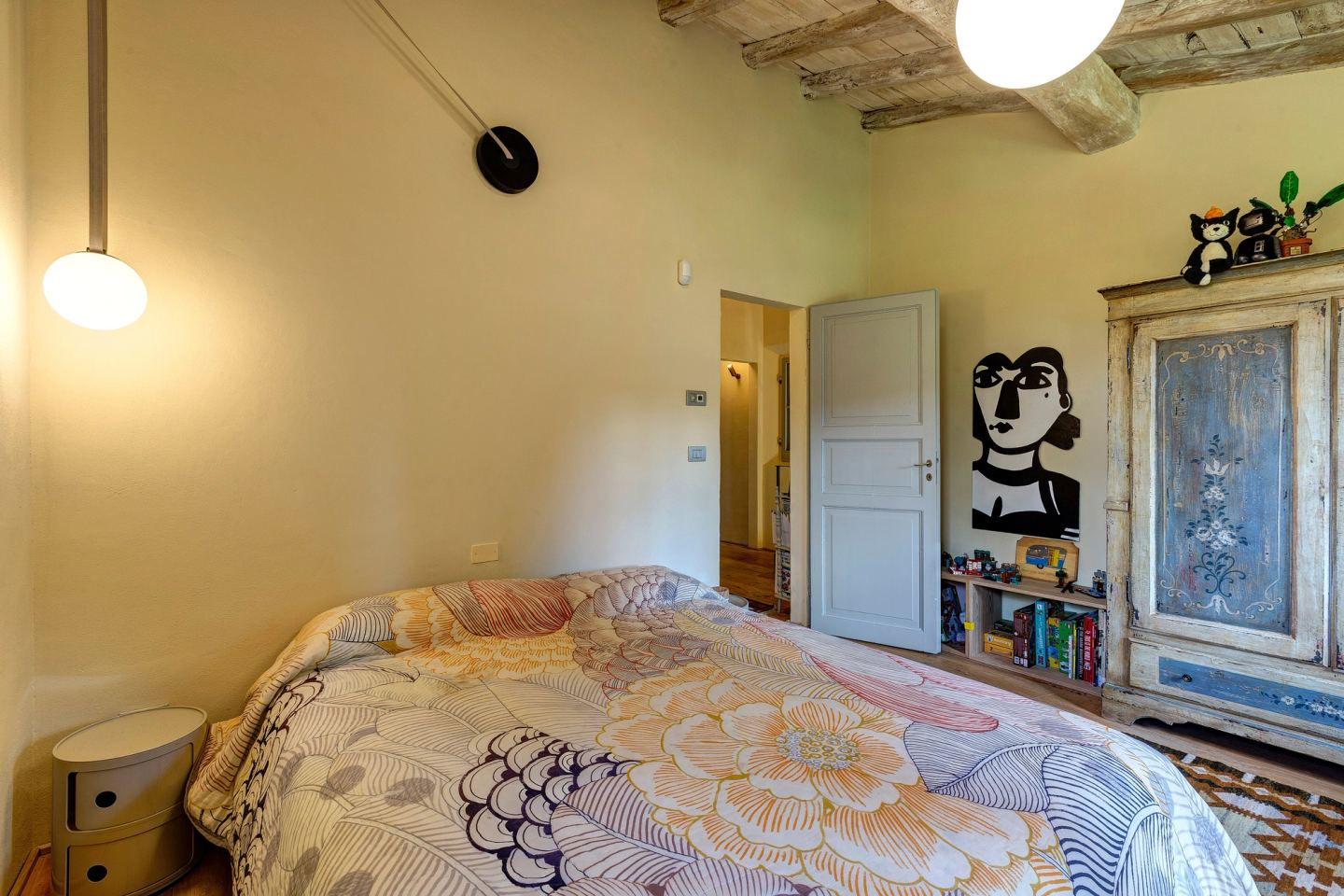 A pendant on a long arm over the bedside table, a painted wardrobe beyond