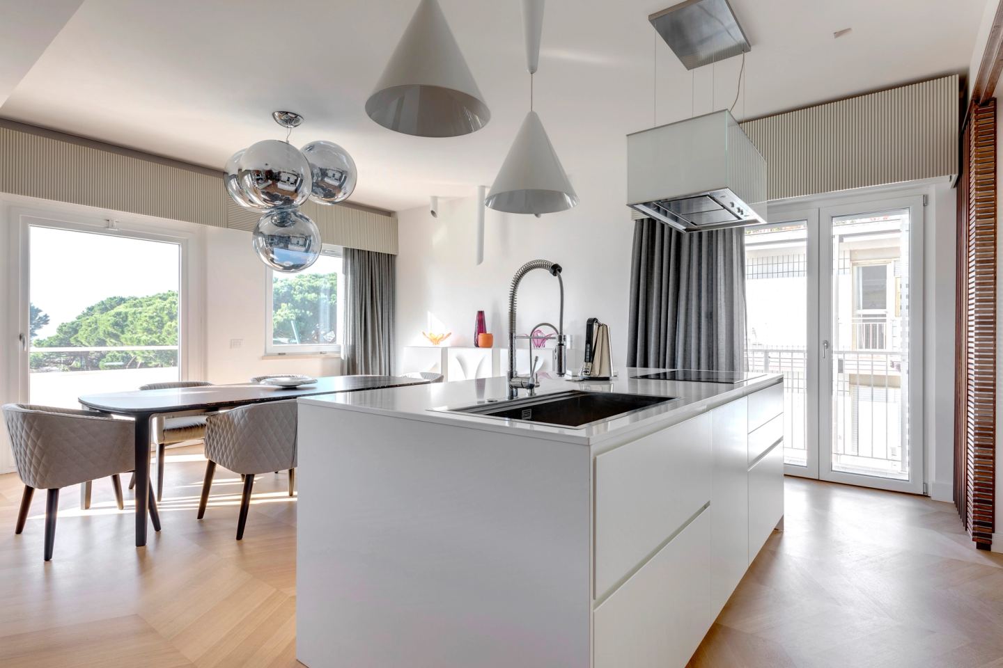 White kitchen island with conical pendants, dining table beyond